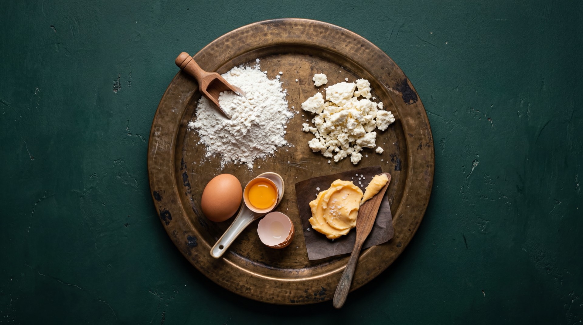 Ingredientes de las Achiras Ramo: almidon de achira puro tamizado, queso cuajada fresco rallado, mantequilla sin sal, huevos criollos y sal fina sobre mesa oscura