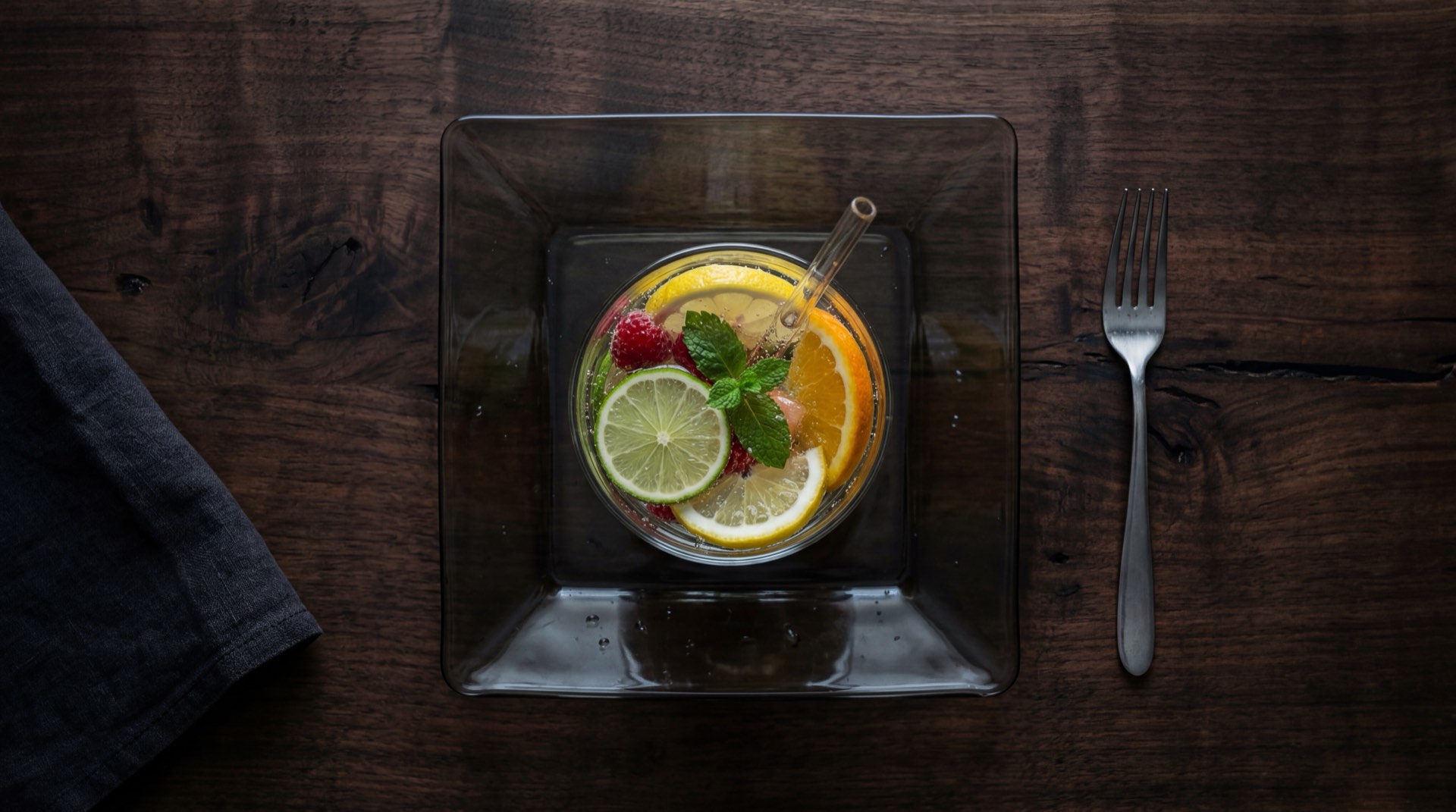 Agua saborizada casera con rodajas de limon tahiti fresco, hojas de menta verde, rodajas de pepino cohombro y jengibre fresco en jarra de vidrio transparente