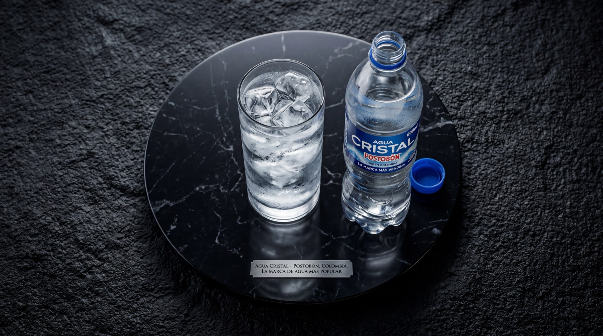 Botella de Agua Cristal natural de Postobon sobre mesa de marmol negro con vetas doradas