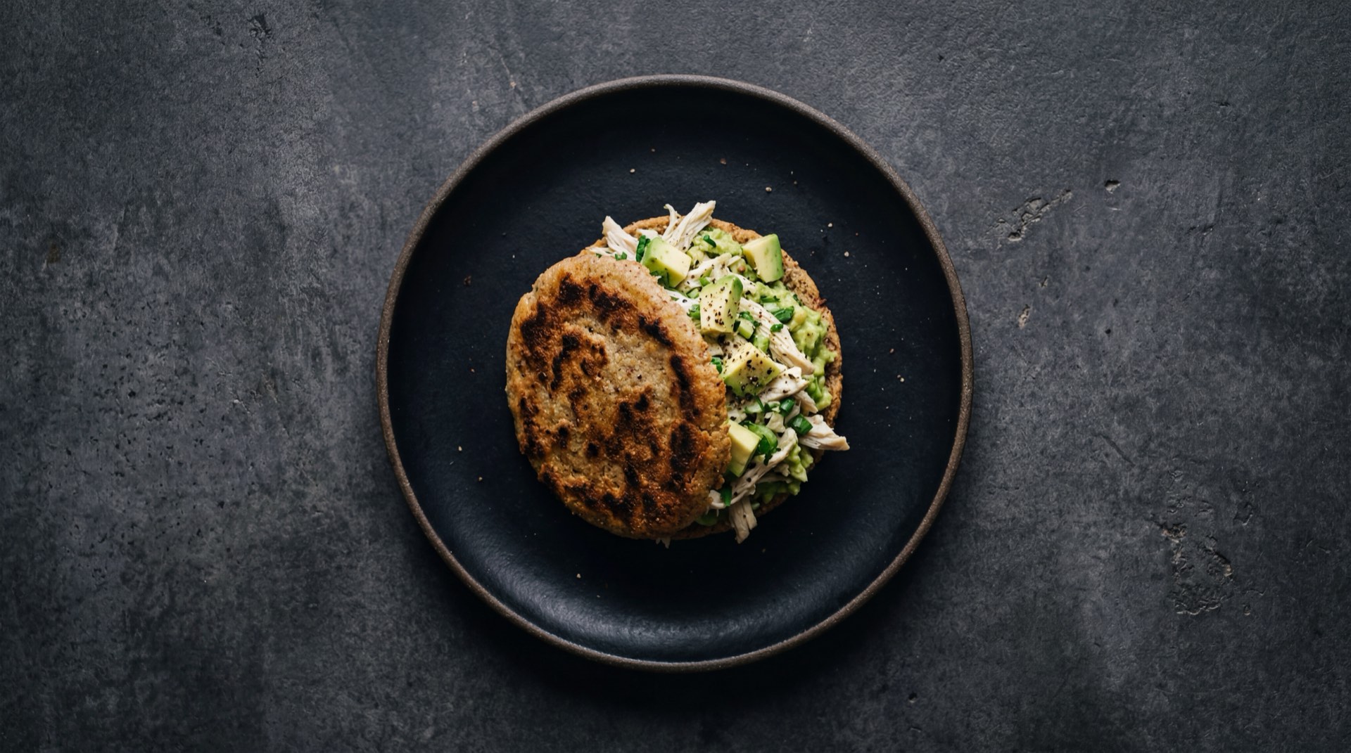 Arepa venezolana version saludable asada sin aceite rellena de pollo desmechado a la plancha con aguacate maduro y tomate rojo en rodajas