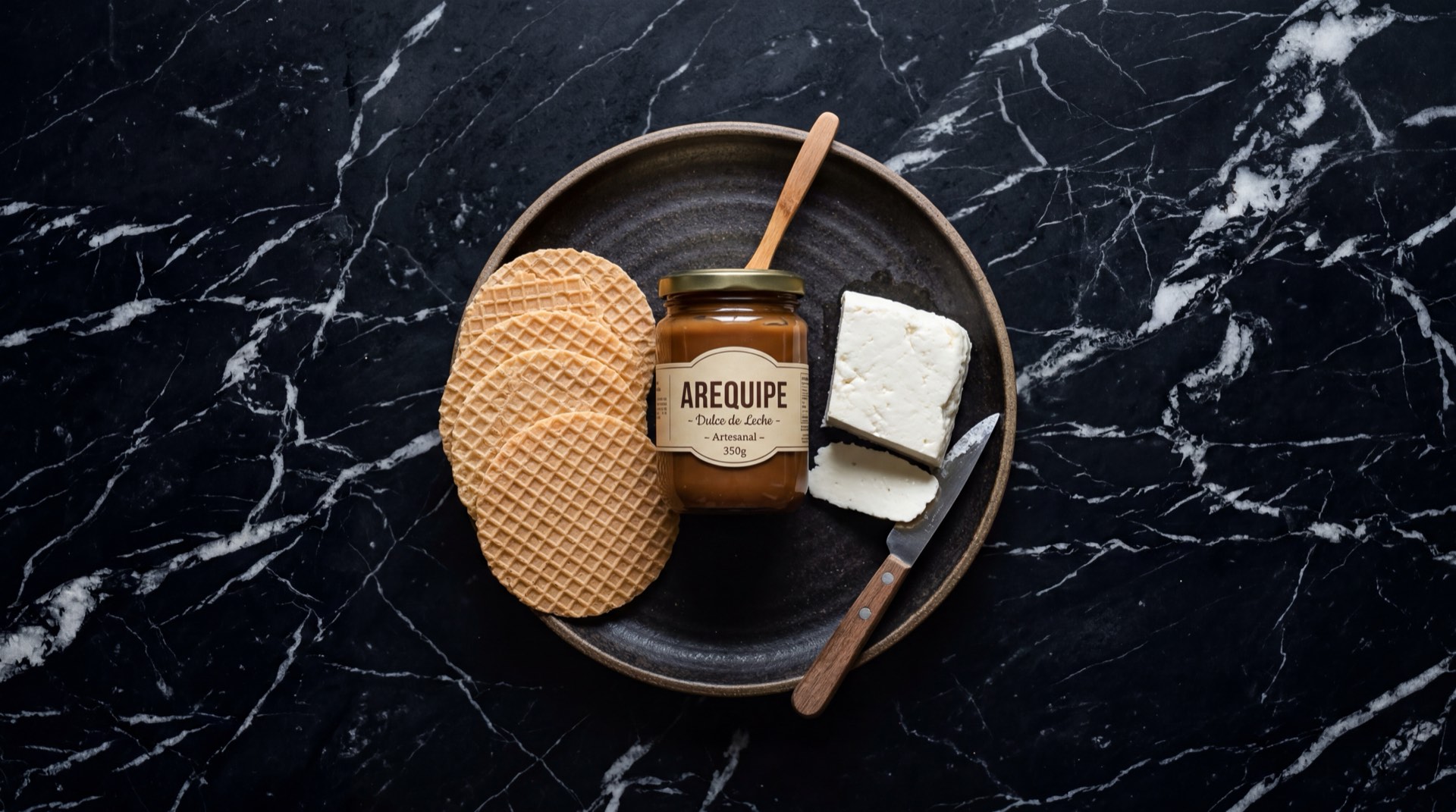 Ingredientes del Arequipe Alpina: leche fresca de vaca entera, azucar blanca refinada, bicarbonato de sodio y vainilla natural sobre superficie de madera oscura