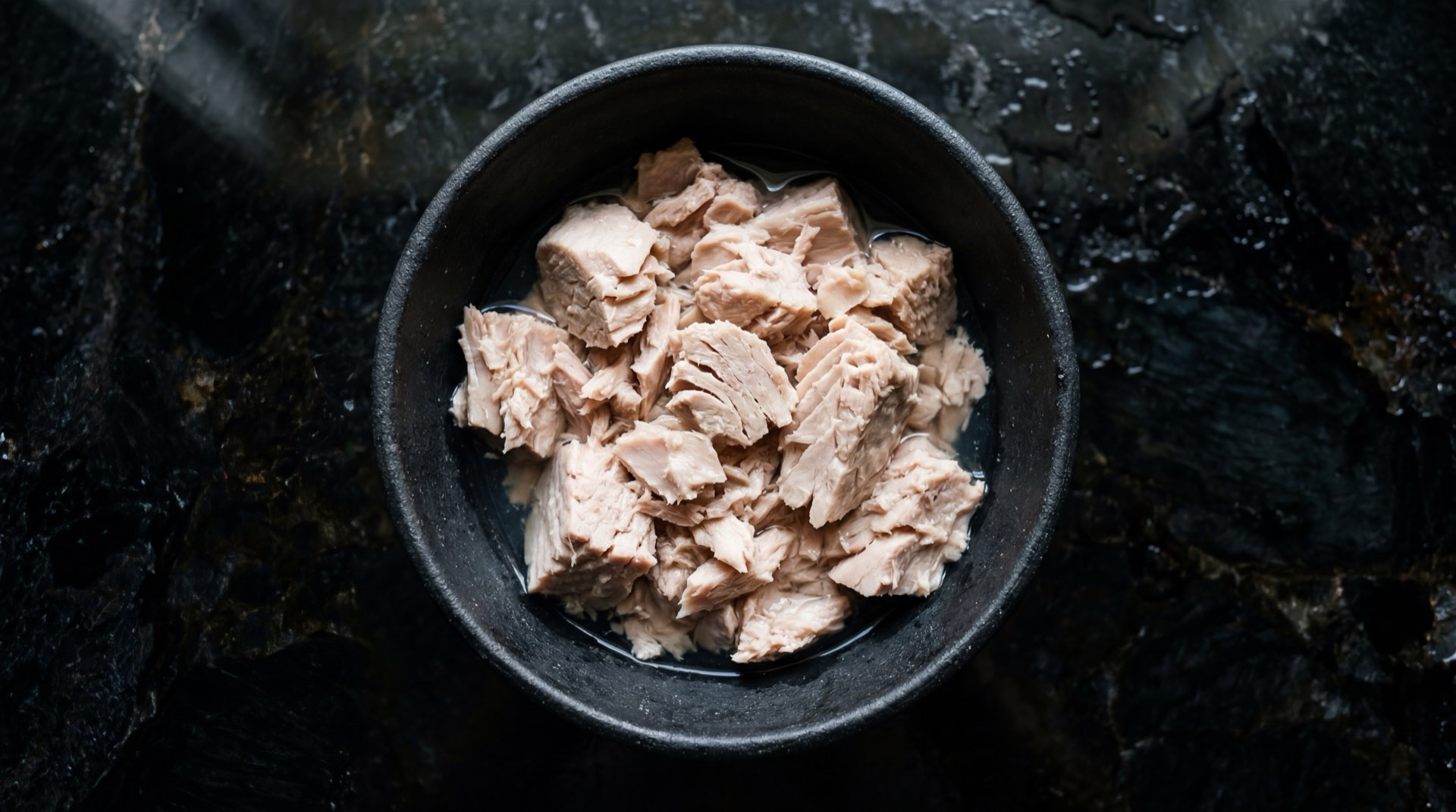 Ensalada de atun colombiana saludable sin mayonesa con aguacate maduro, tomate rojo maduro y limon verde fresco sobre plato de ceramica verde oscuro