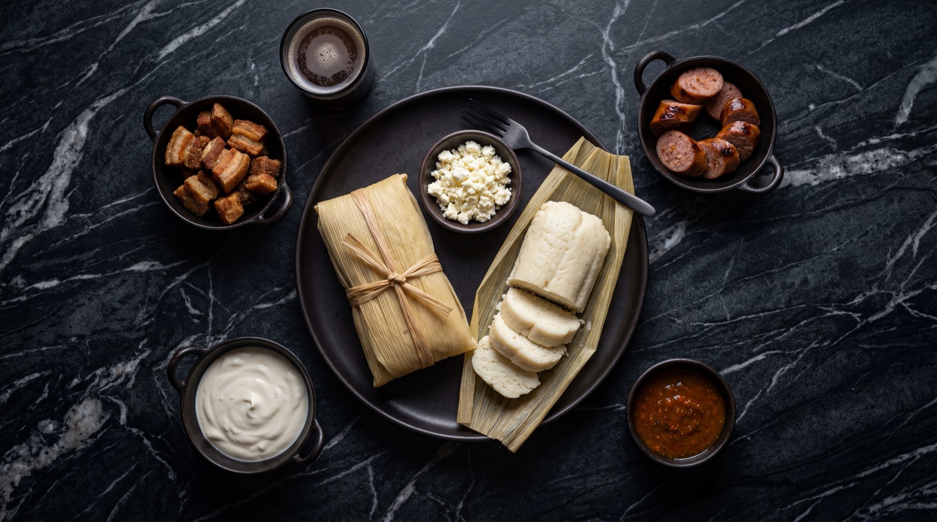 Bollo limpio costeno envuelto en hoja de mazorca sobre plato de ceramica oscura