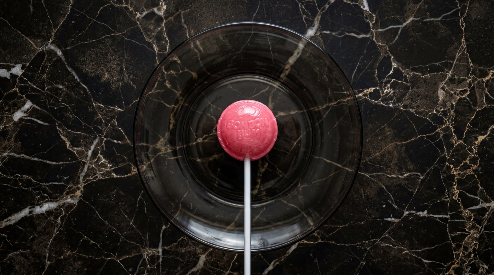 Bon Bon Bum de Colombina, chupete de fresa con centro de chicle sobre piedra de basalto volcanico oscuro