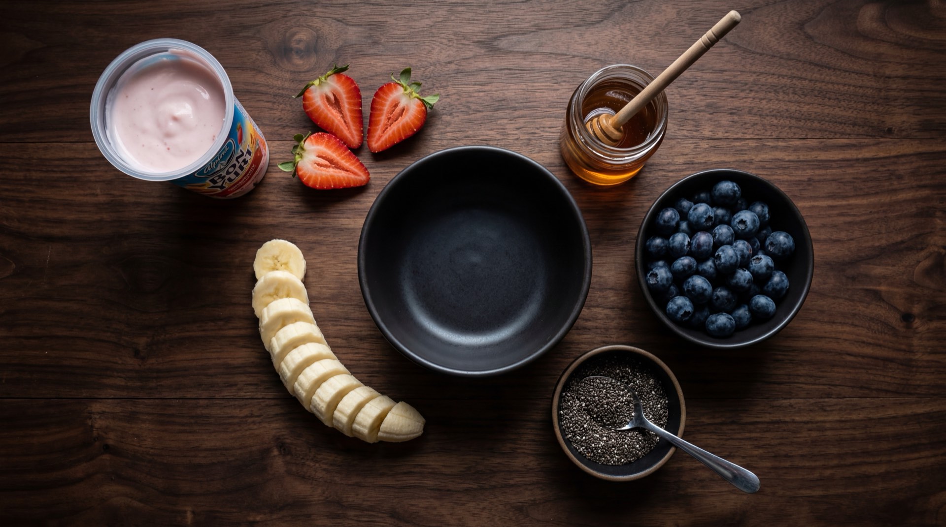Bon Yurt abierto mostrando el compartimento de yogur saborizado de fresa y el compartimento de cereal crocante de trigo, con leche fresca y fresas al lado