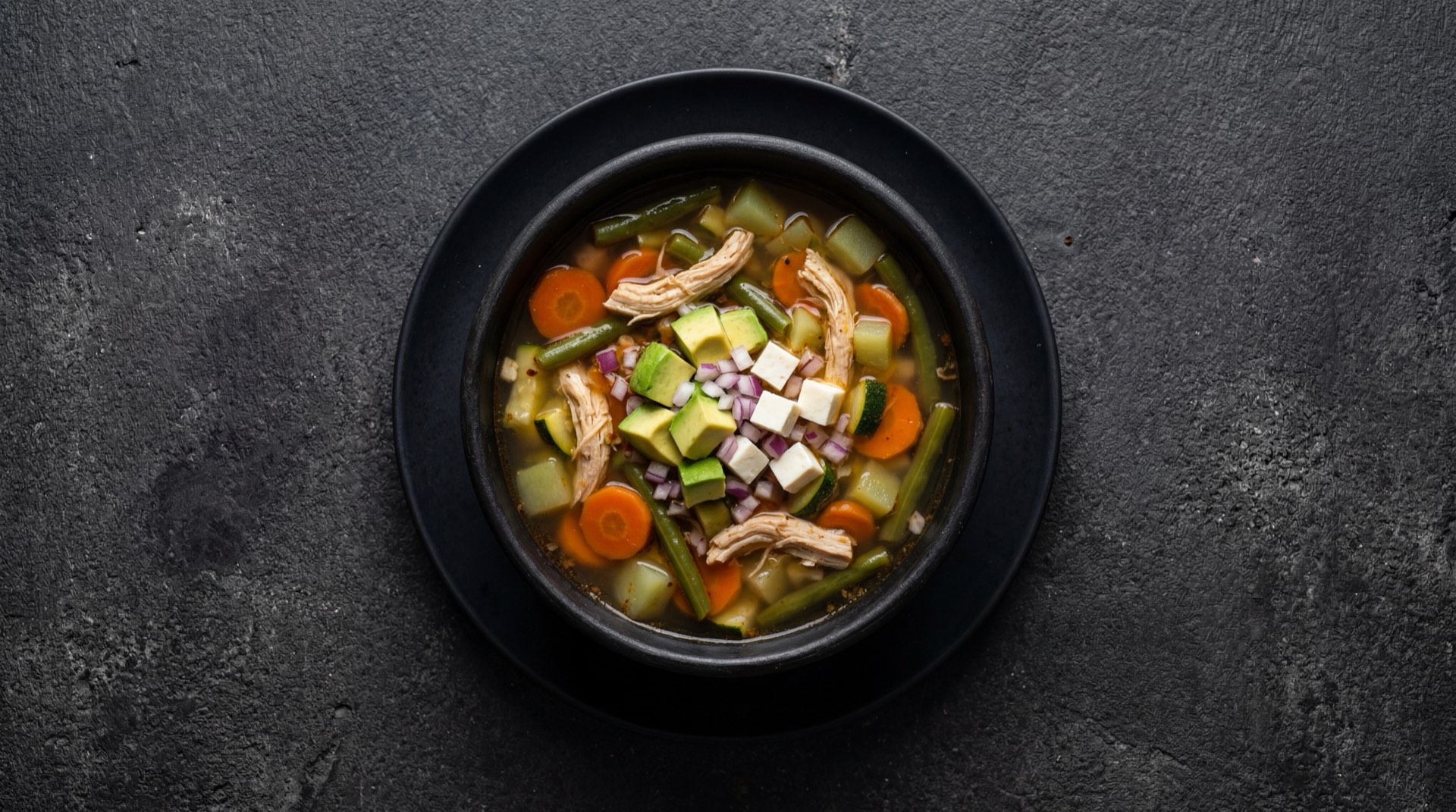 Caldo tlalpeno version ligera sin aceite con mas verduras y pollo sin piel sobre mesa oscura