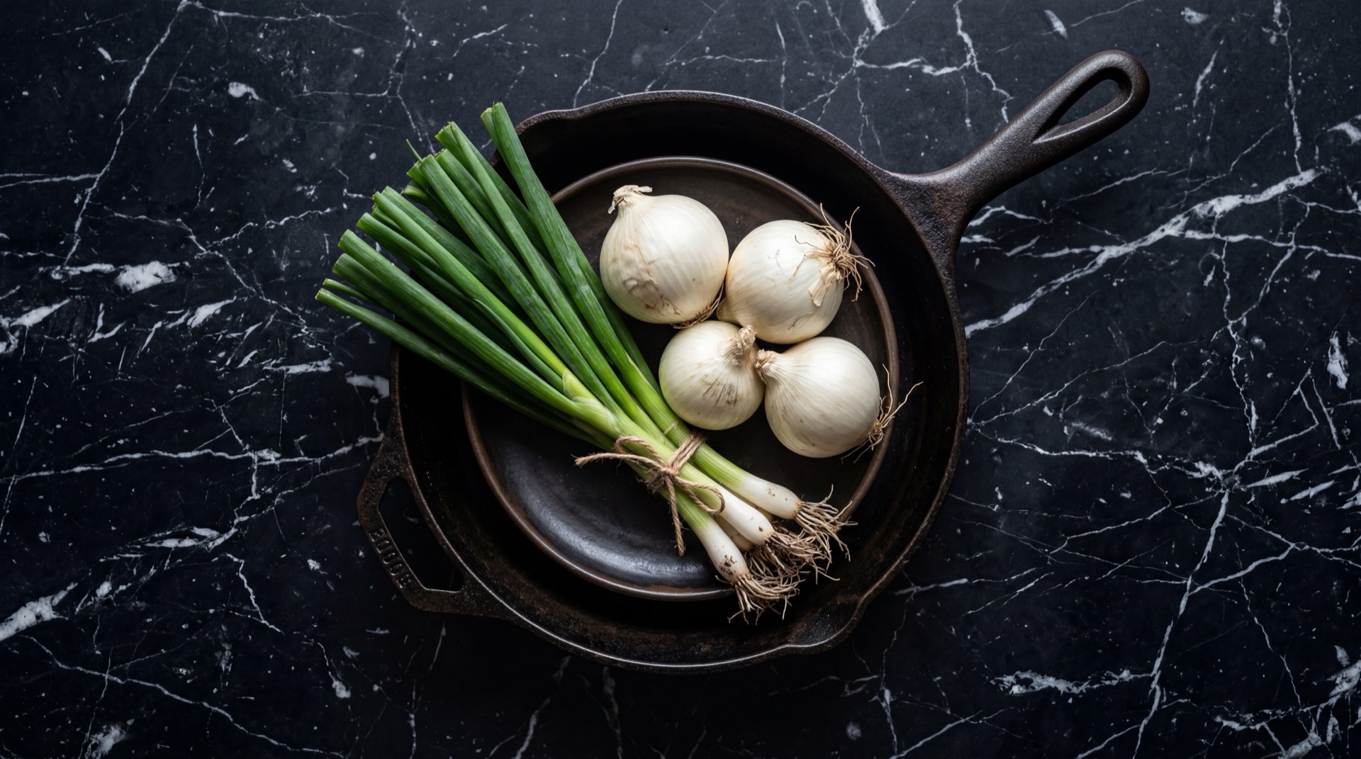 Cebolla larga fresca colombiana y cebolla cabezona blanca sobre tabla de madera de acacia oscura en mesa de granito negro con vetas doradas