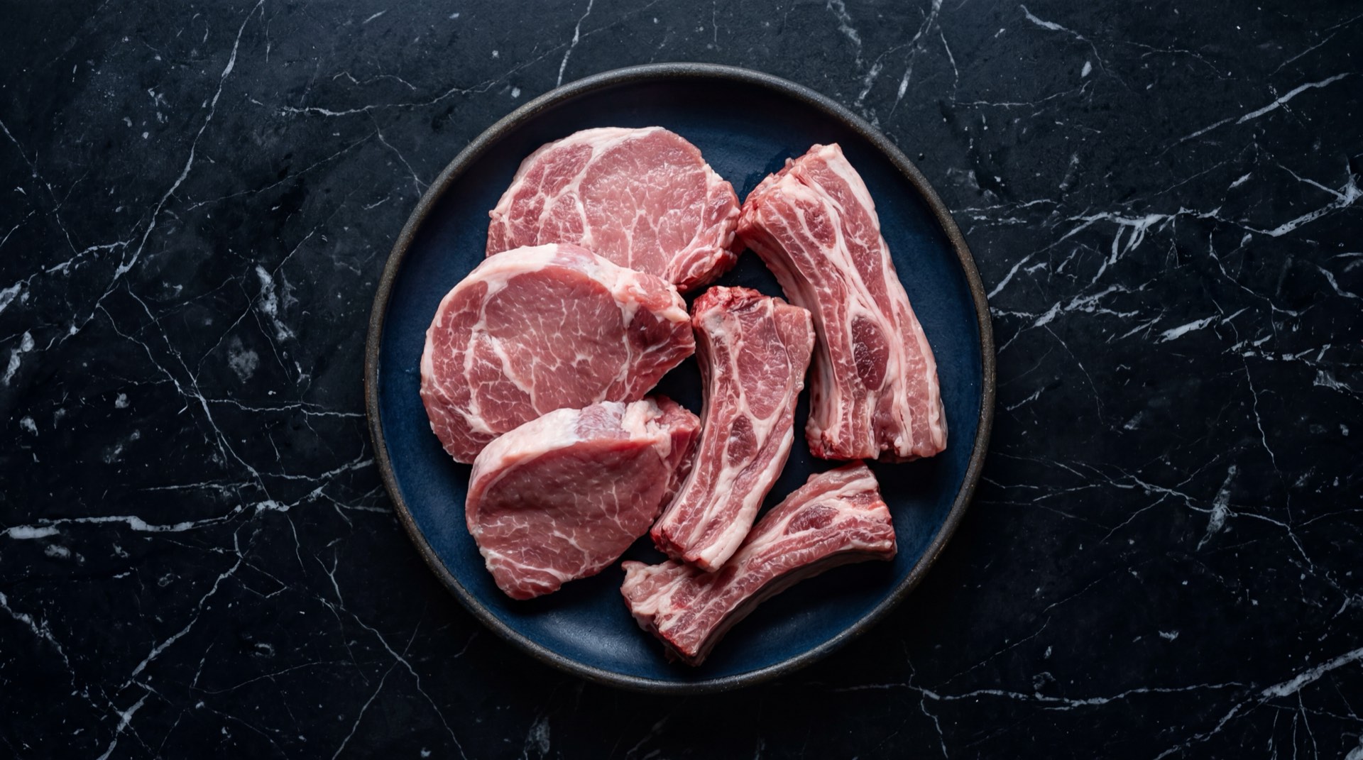 Cortes de cerdo colombiano: lomo de cerdo magro, costilla de cerdo asada y chicharron crujiente sobre tabla de madera de acacia