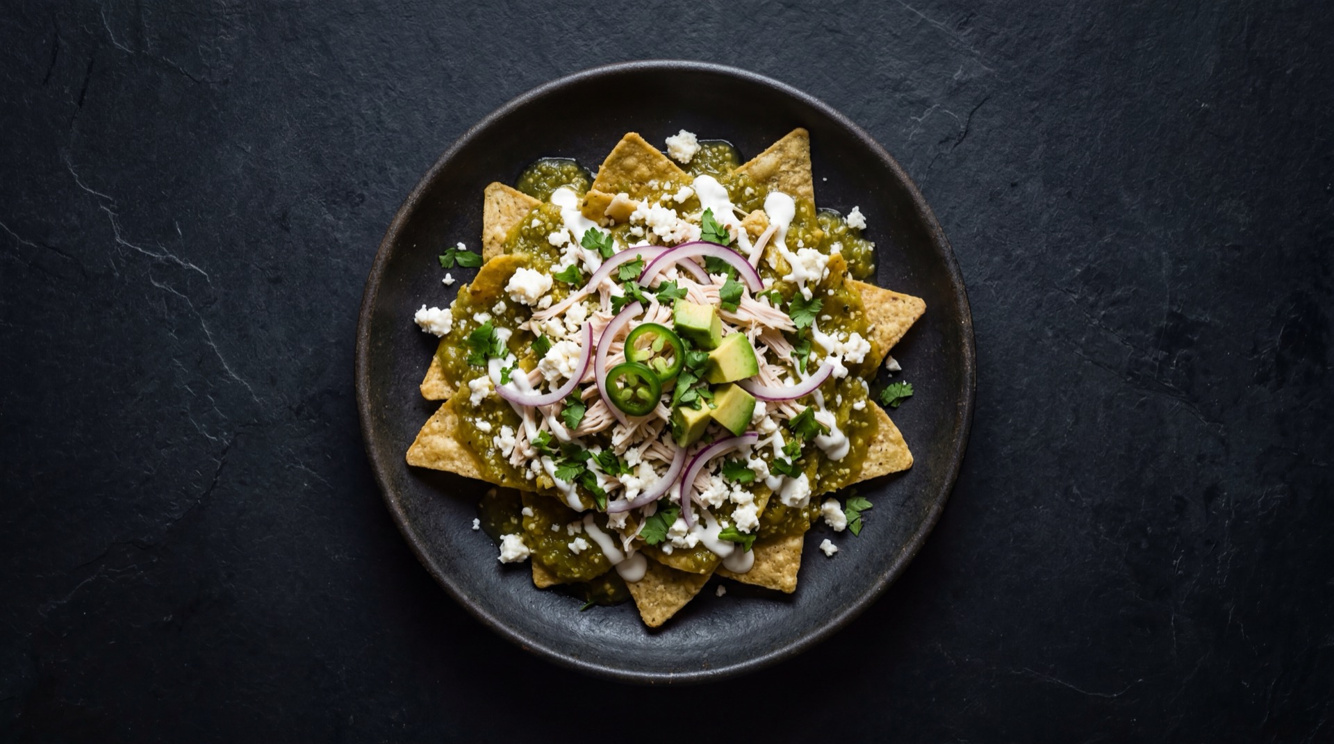 Chilaquiles verdes mexicanos version saludable con totopos de tortilla de maiz horneados sin freir, salsa verde de tomatillo fresco, aguacate en rodajas y queso panela bajo en grasa