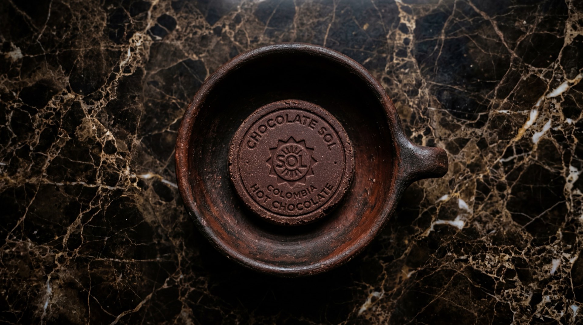 Pastilla de Chocolate Sol de Nacional de Chocolates en empaque amarillo sobre mesa de marmol oscuro