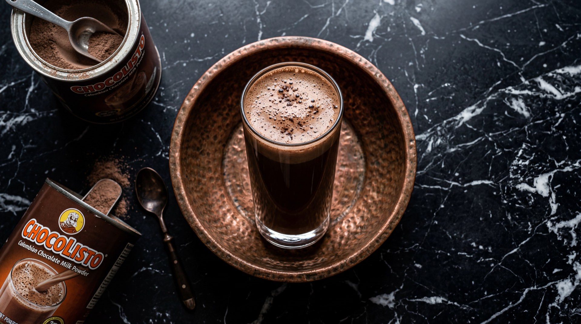 Vaso de Chocolisto caliente con leche sobre mesa de marmol oscuro, bebida de chocolate en polvo clasica colombiana de Nacional de Chocolates