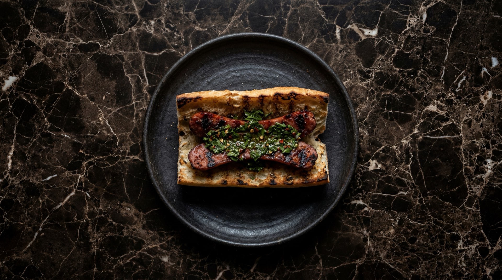 Choripan argentino con chorizo criollo a la parrilla cortado al medio en pan frances crujiente con chimichurri casero argentino