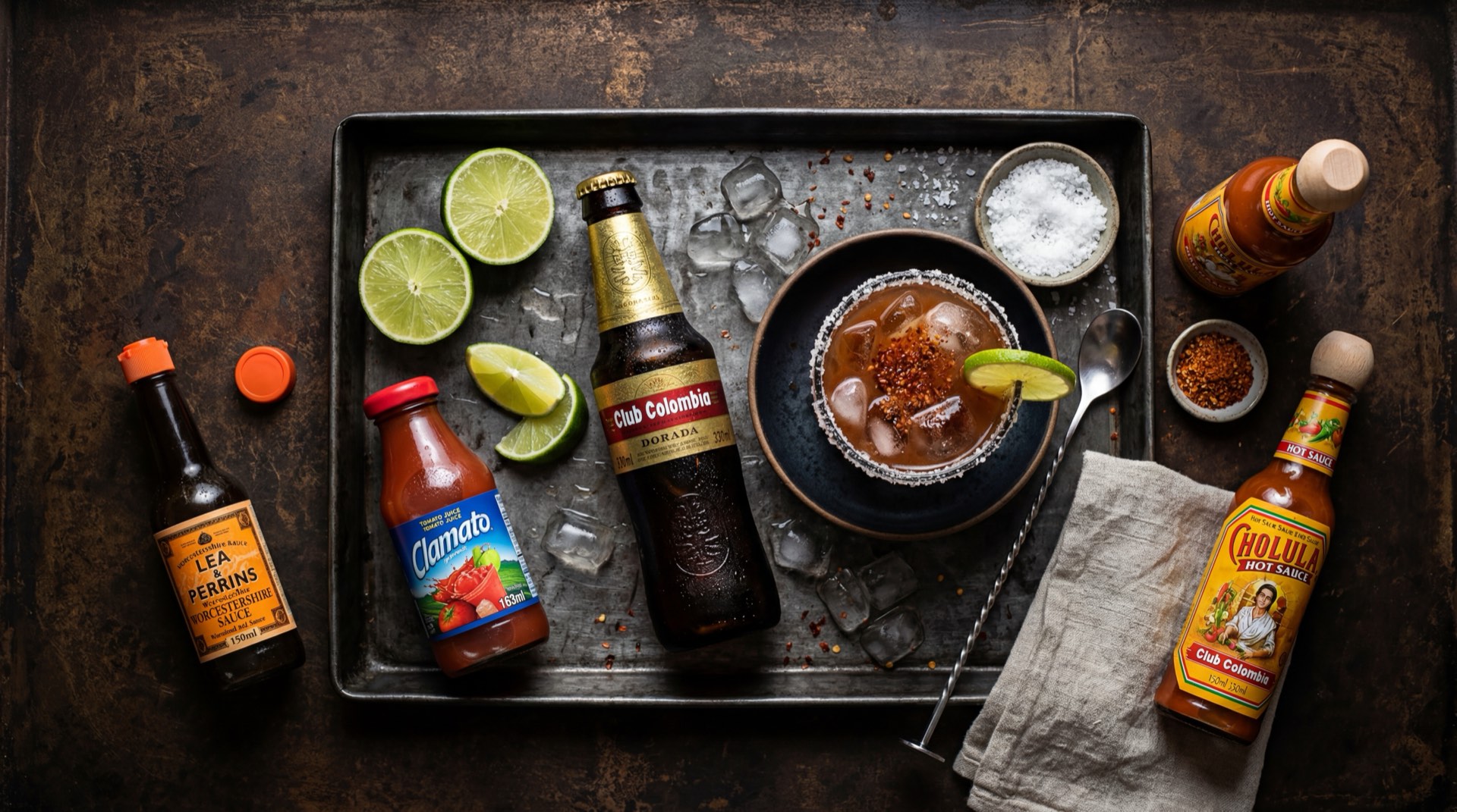 Tres botellas de Club Colombia: Dorada golden lager con etiqueta dorada, Roja red ale con etiqueta roja y Negra dark stout con etiqueta negra, con espigas de cebada malteada y lupulo verde fresco