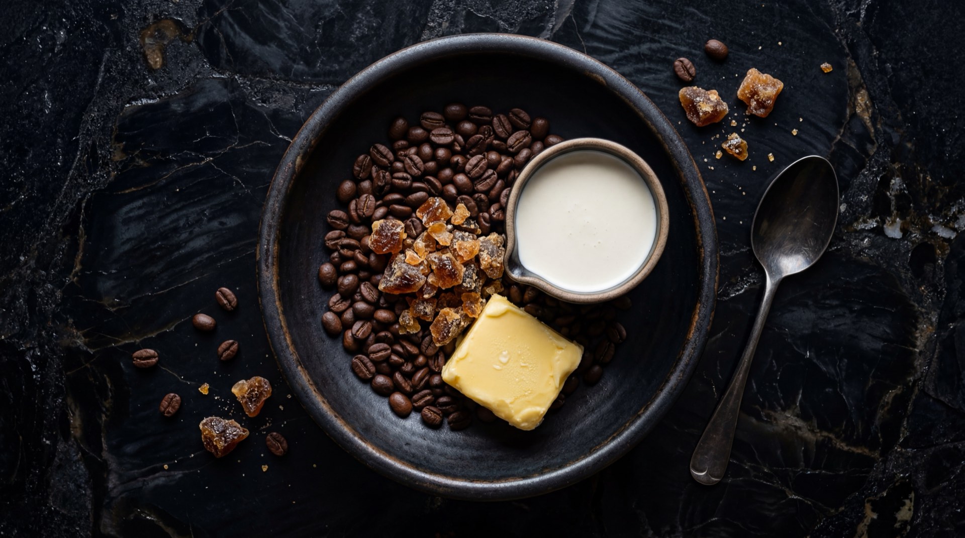 Ingredientes del Coffee Delight: granos de cafe colombiano tostado oscuro, azucar refinada blanca, glucosa liquida transparente y extracto concentrado de cafe sobre mesa oscura