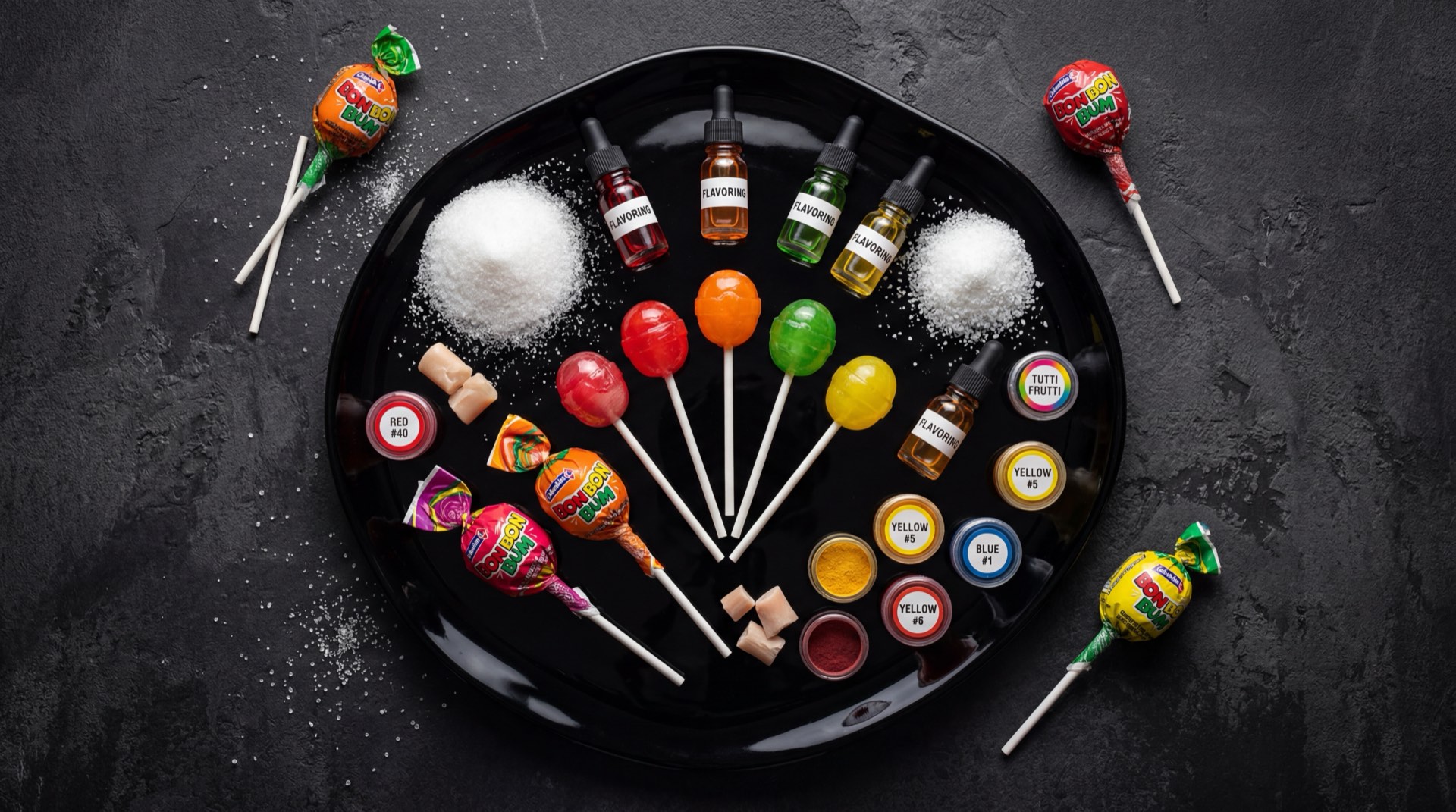 Colombinetas de diferentes sabores abiertas mostrando los colores de fresa roja, uva morada, mango amarillo y limon verde, con palito de plastico blanco visible