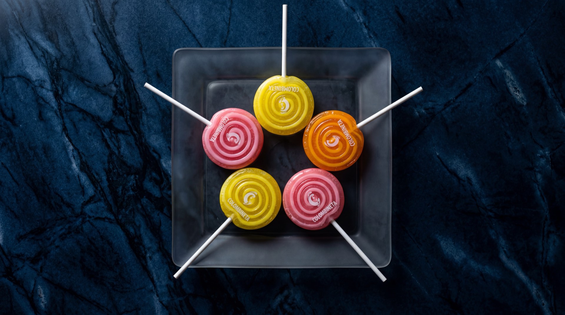 Colombineta de Colombina, chupete duro plano de colores multisabor sobre superficie de marmol negro