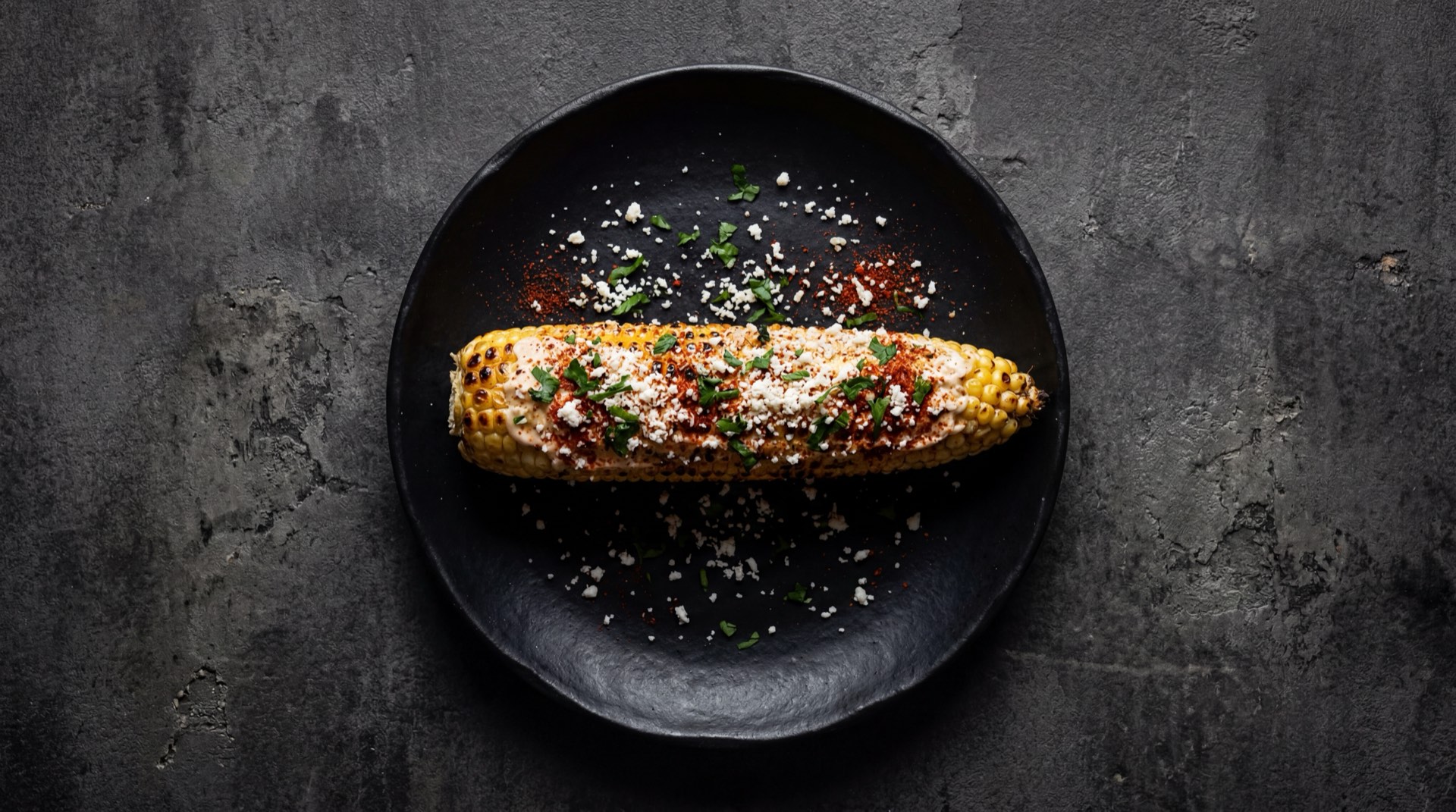 Elote mexicano version saludable asado al carbon sin mayonesa, con limon verde, chile en polvo rojo y queso cotija rallado