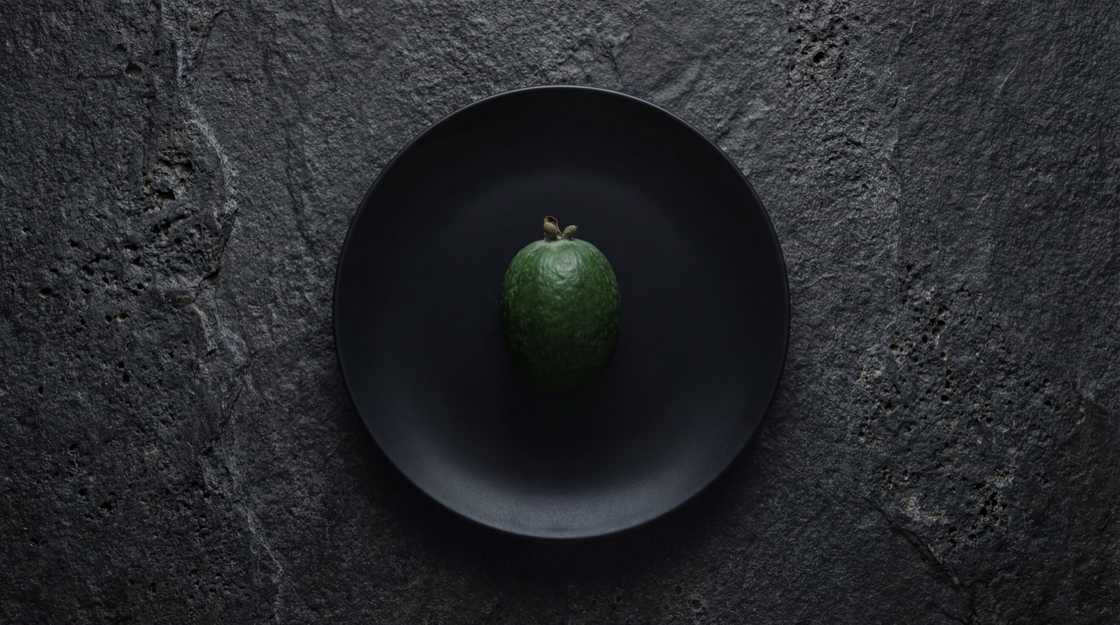 Feijoas enteras y cortadas mostrando su pulpa cremosa