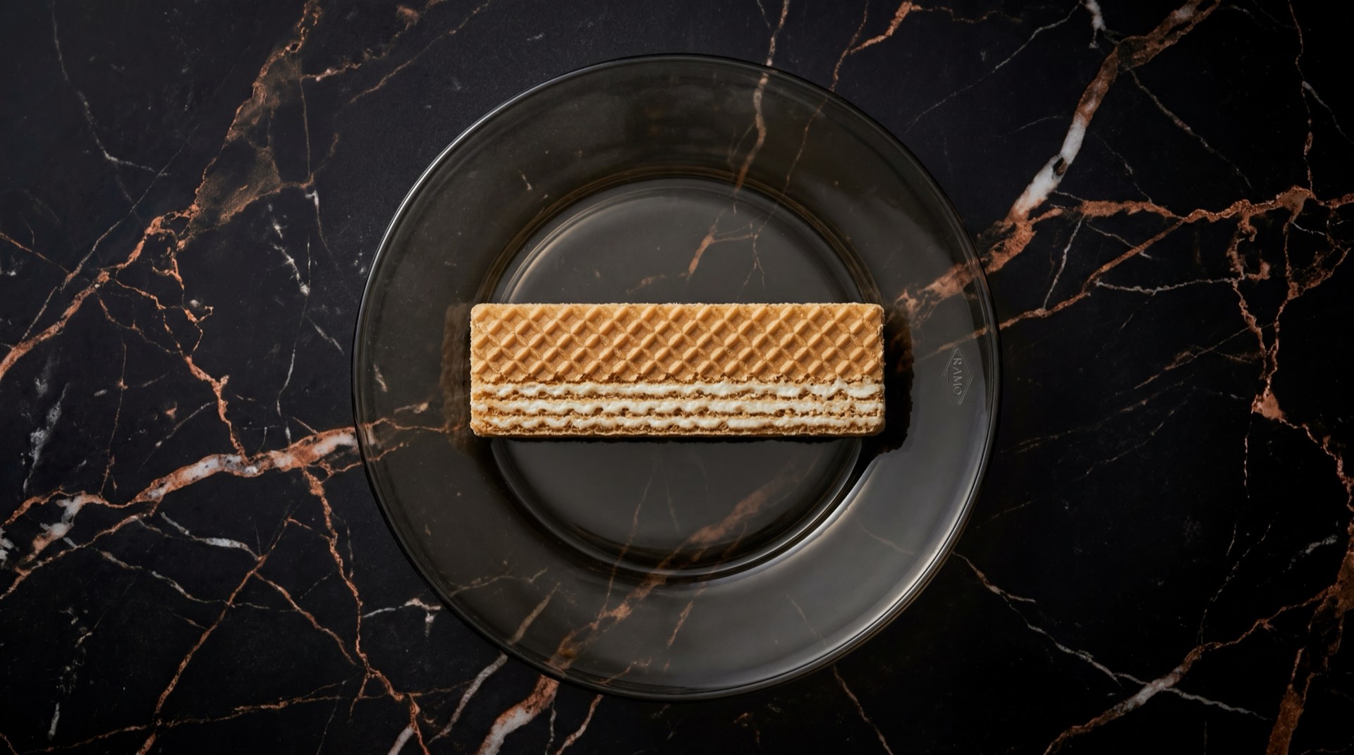 Gala de Ramo, galleta wafer rectangular rellena de crema de vainilla sobre plato de ceramica oscura