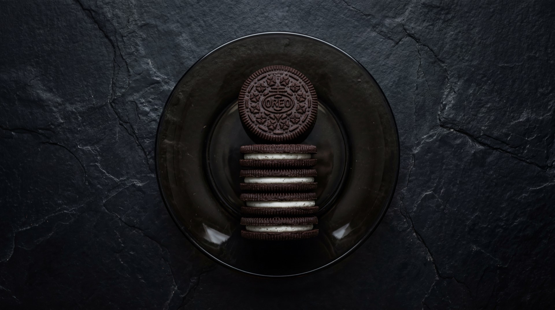 Galletas Oreo Original de Mondelez, tres galletas de chocolate con relleno de crema de vainilla sobre plato de ceramica negro