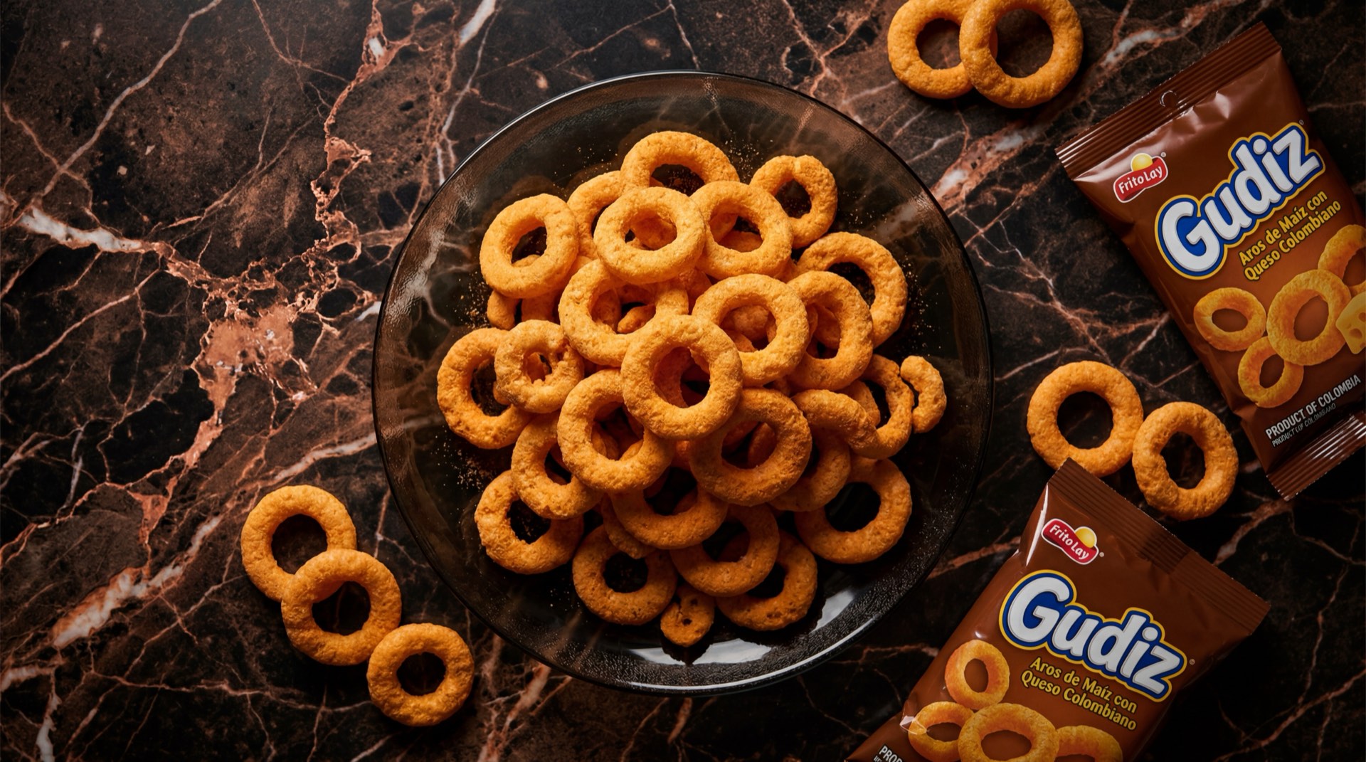 Gudiz de Frito Lay, anillos de maiz inflado sabor a queso color naranja brillante sobre plato de ceramica oscura