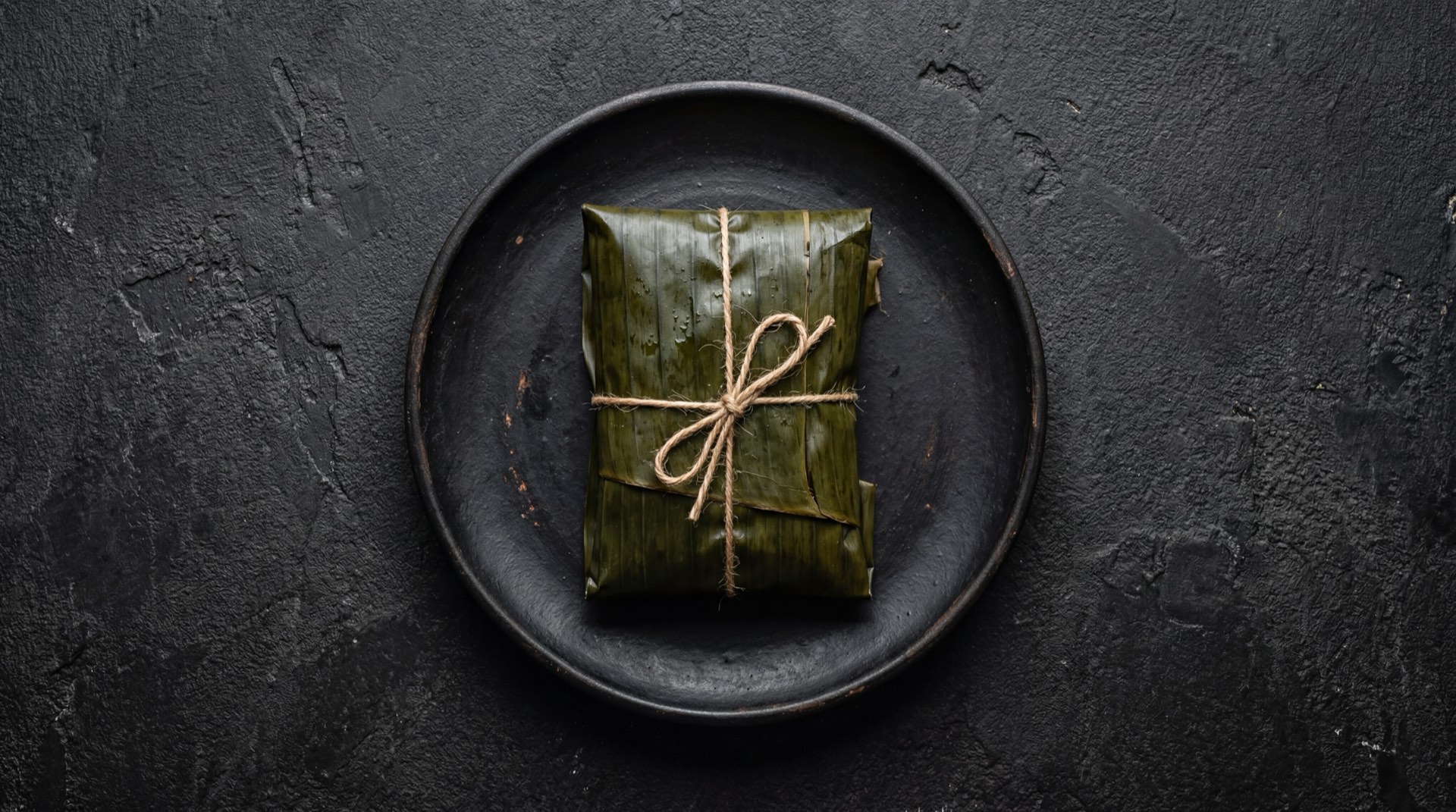 Hallaca venezolana version mas ligera con menos masa de maiz, mas pollo desmechado y menos cerdo sobre hoja de platano fresca