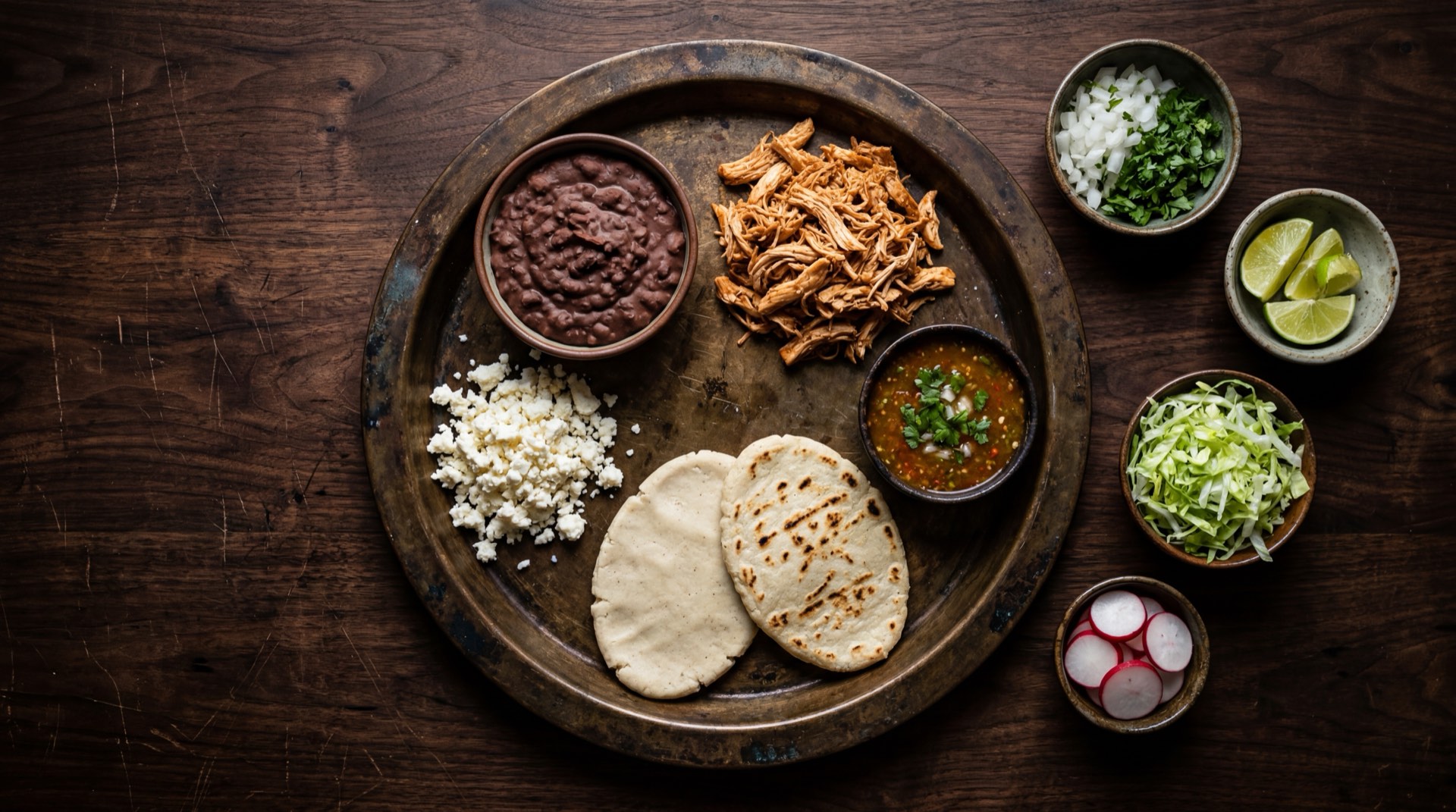 Ingredientes del huarache mexicano: masa de maiz fresca nixtamalizada, frijoles refritos negros espesos, bistec de res en tiras, queso fresco desmoronado, salsa verde cruda de tomatillo, crema acida mexicana, lechuga romana picada y cebolla blanca fresca