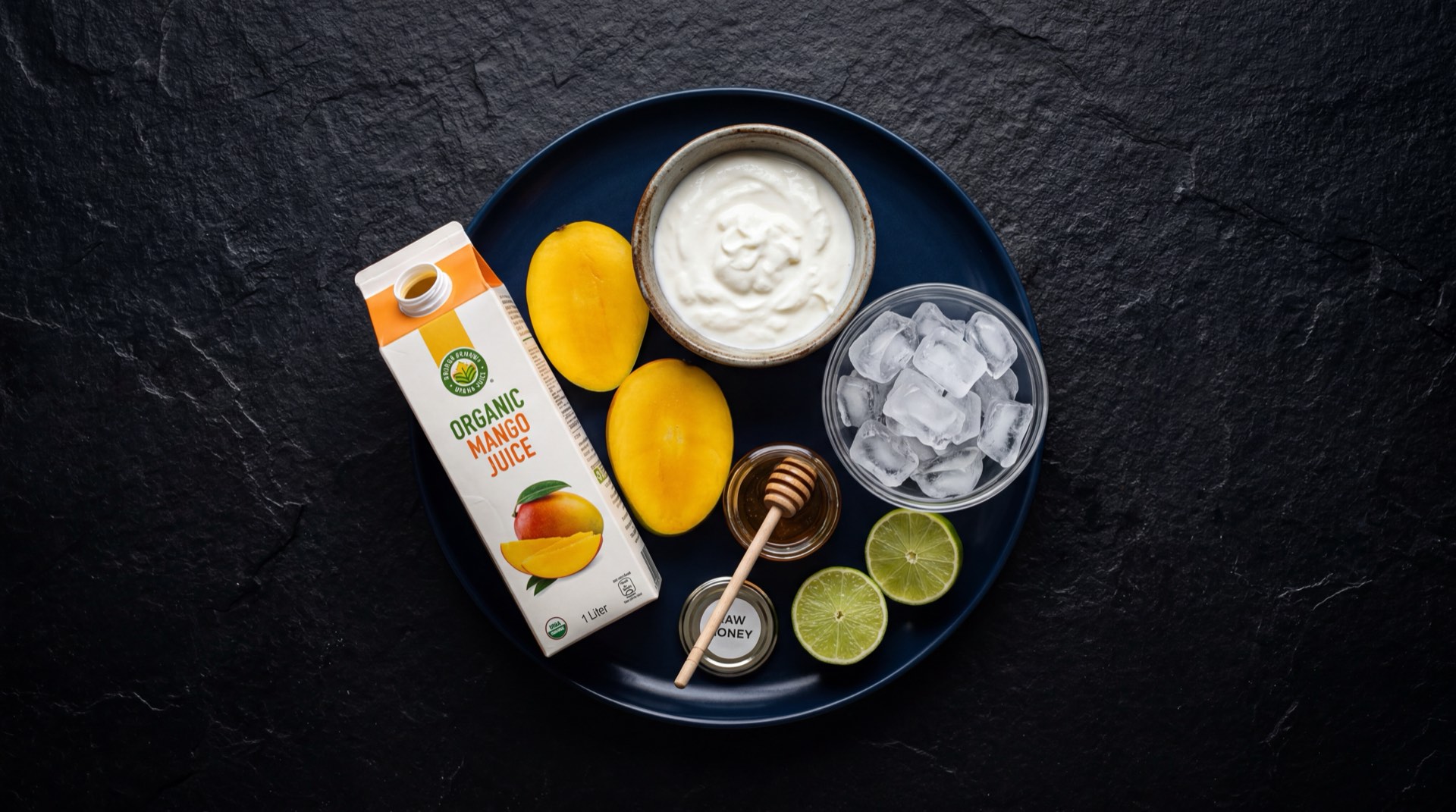 Caja de jugo Hit de mango abierta junto a mango fresco cortado en tajadas sobre superficie oscura