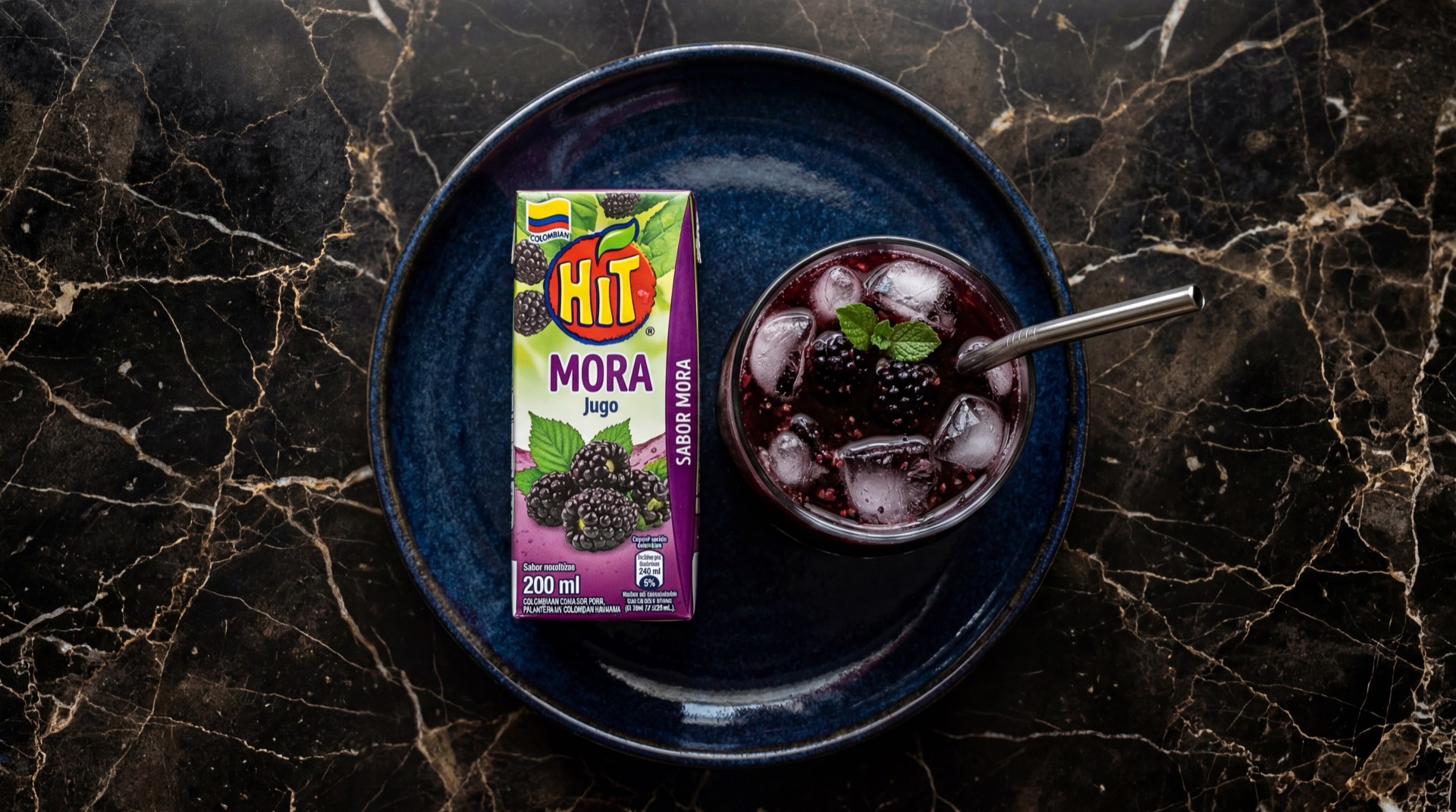 Caja de jugo Hit de mora de Postobon sobre superficie oscura con color morado intenso