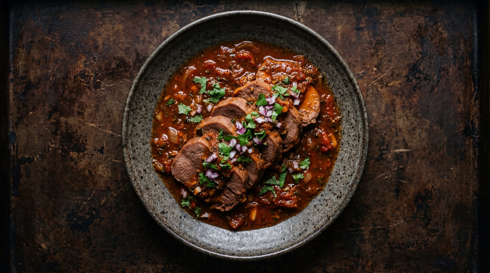Lengua en salsa colombiana con rodajas de lengua de res banadas en salsa criolla de tomate rojo maduro y cebolla larga fresca sobre plato de ceramica negro mate