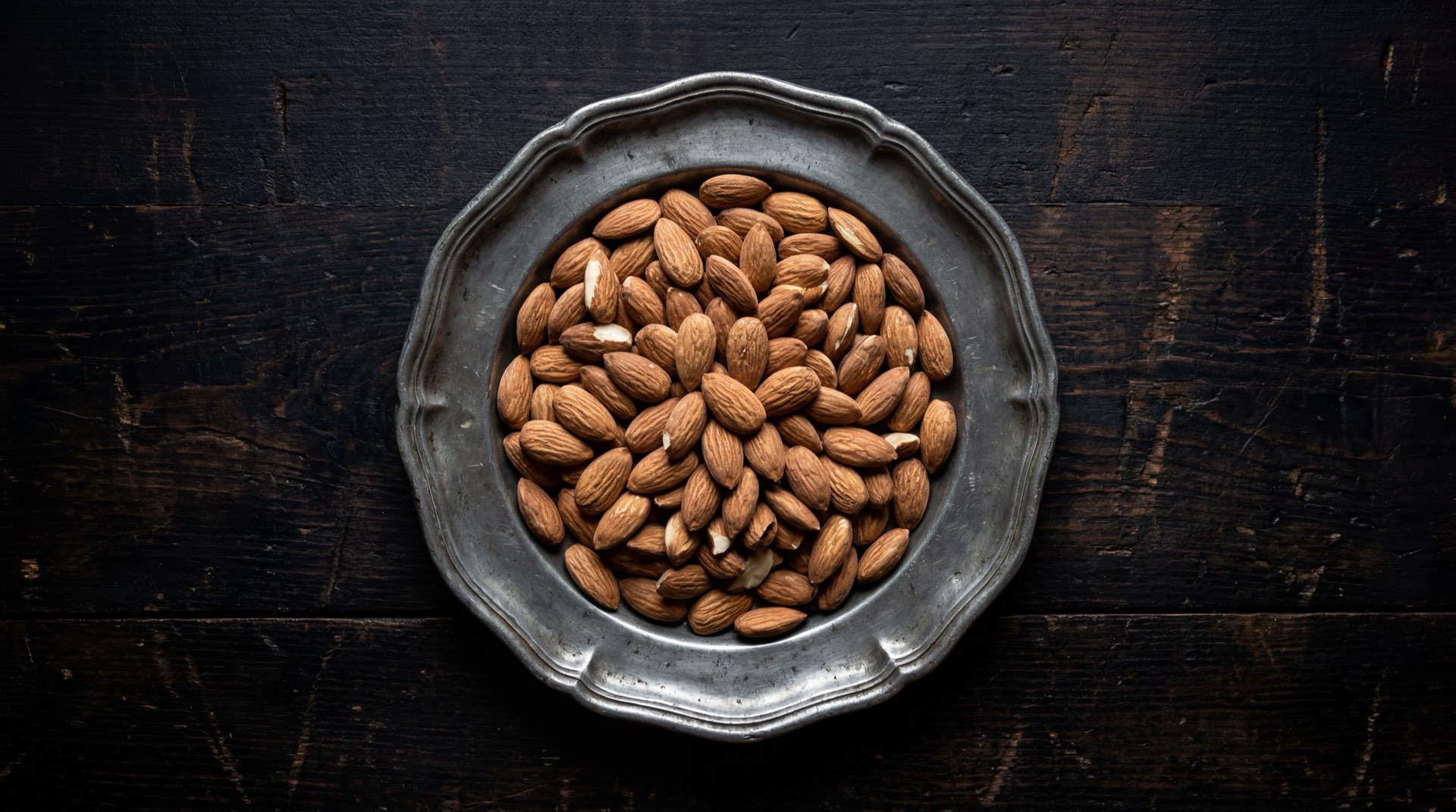 Alternativa saludable al Manimoto: mani natural tostado sin sal con almendras crudas y semillas de calabaza en bowl de ceramica oscura