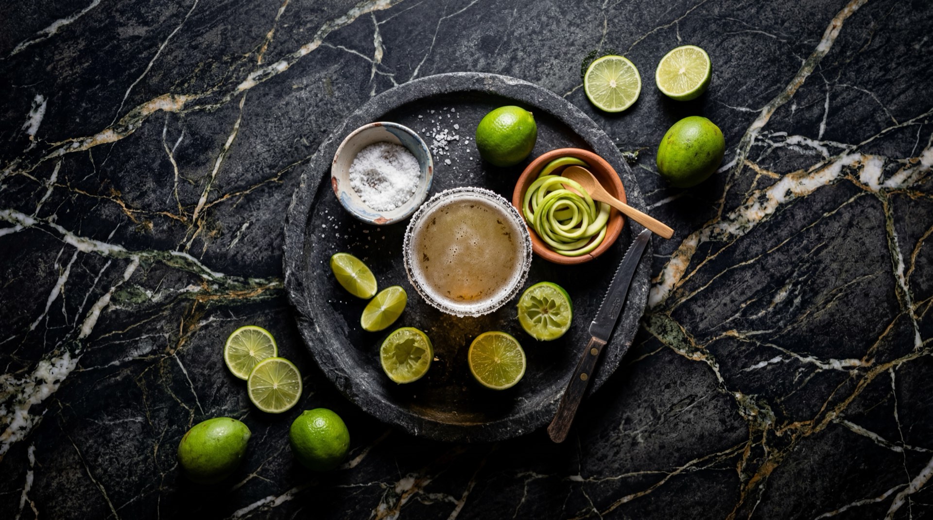 Michelada colombiana con cerveza lager bien fria, jugo de limon verde fresco, sal gruesa en el borde y hielo en cubos grandes en vaso alto de vidrio