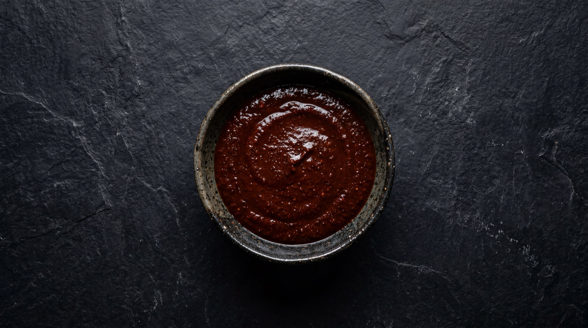 Mole Rojo mexicano tradicional servido en plato oscuro sobre mesa de marmol negro