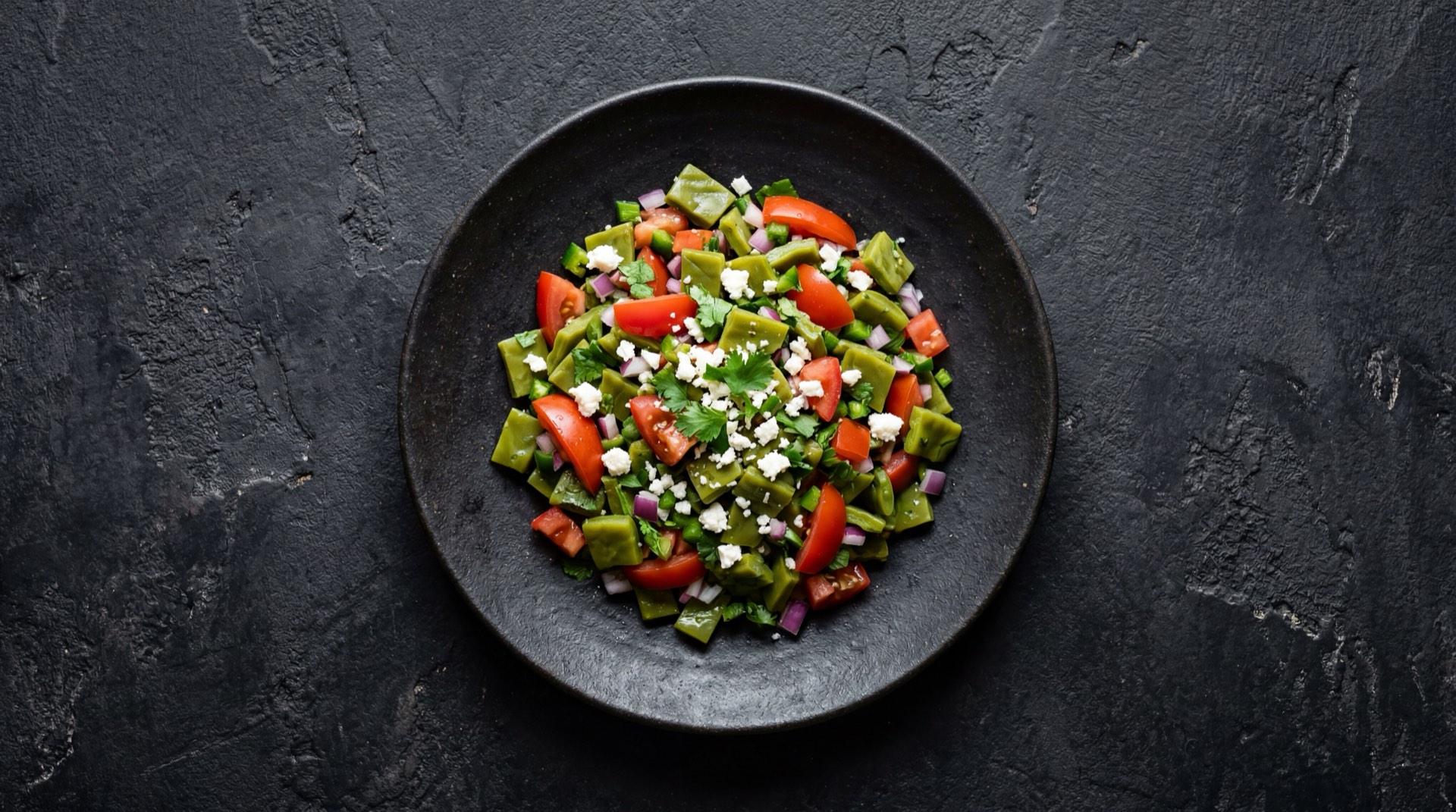 Ensalada fresca de nopales mexicanos con tomate rojo maduro, cebolla blanca, cilantro fresco, queso fresco desmoronado y limon verde