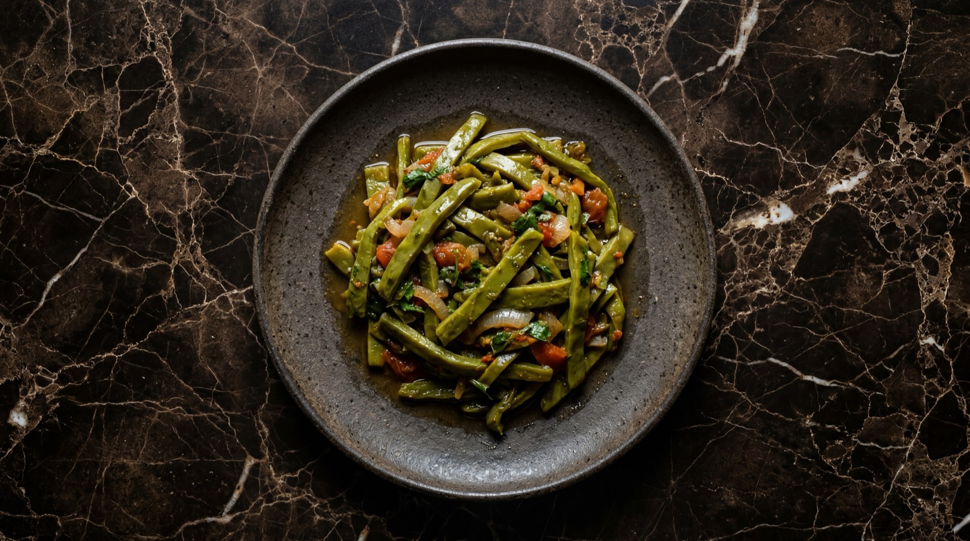 Nopales mexicanos asados a la mexicana con cebolla blanca y tomate rojo en comal de hierro sobre mesa de concreto oscuro