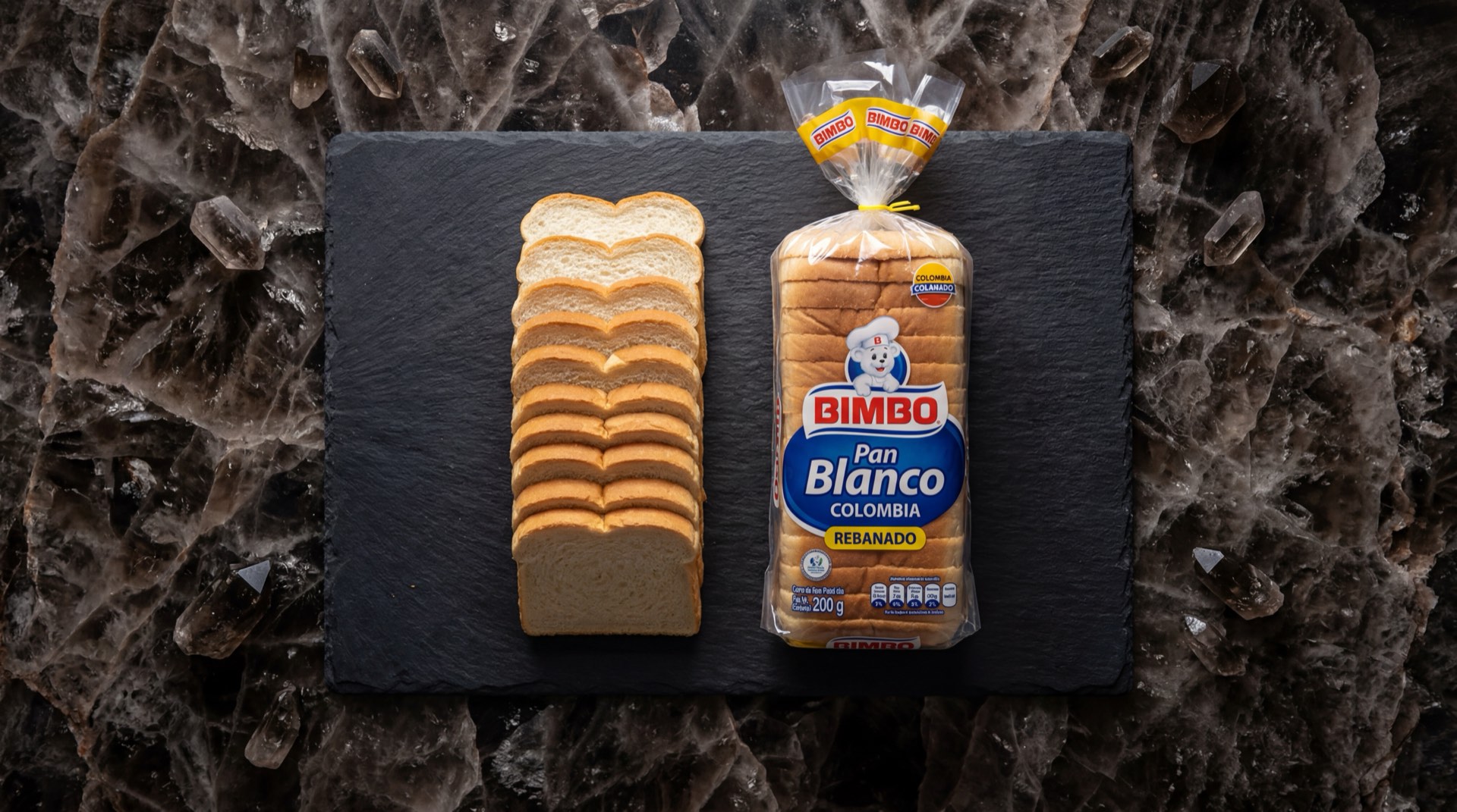 Pan Bimbo blanco tajado en bolsa sobre mesa de granito oscuro, rebanadas de pan suave de trigo blanco visibles