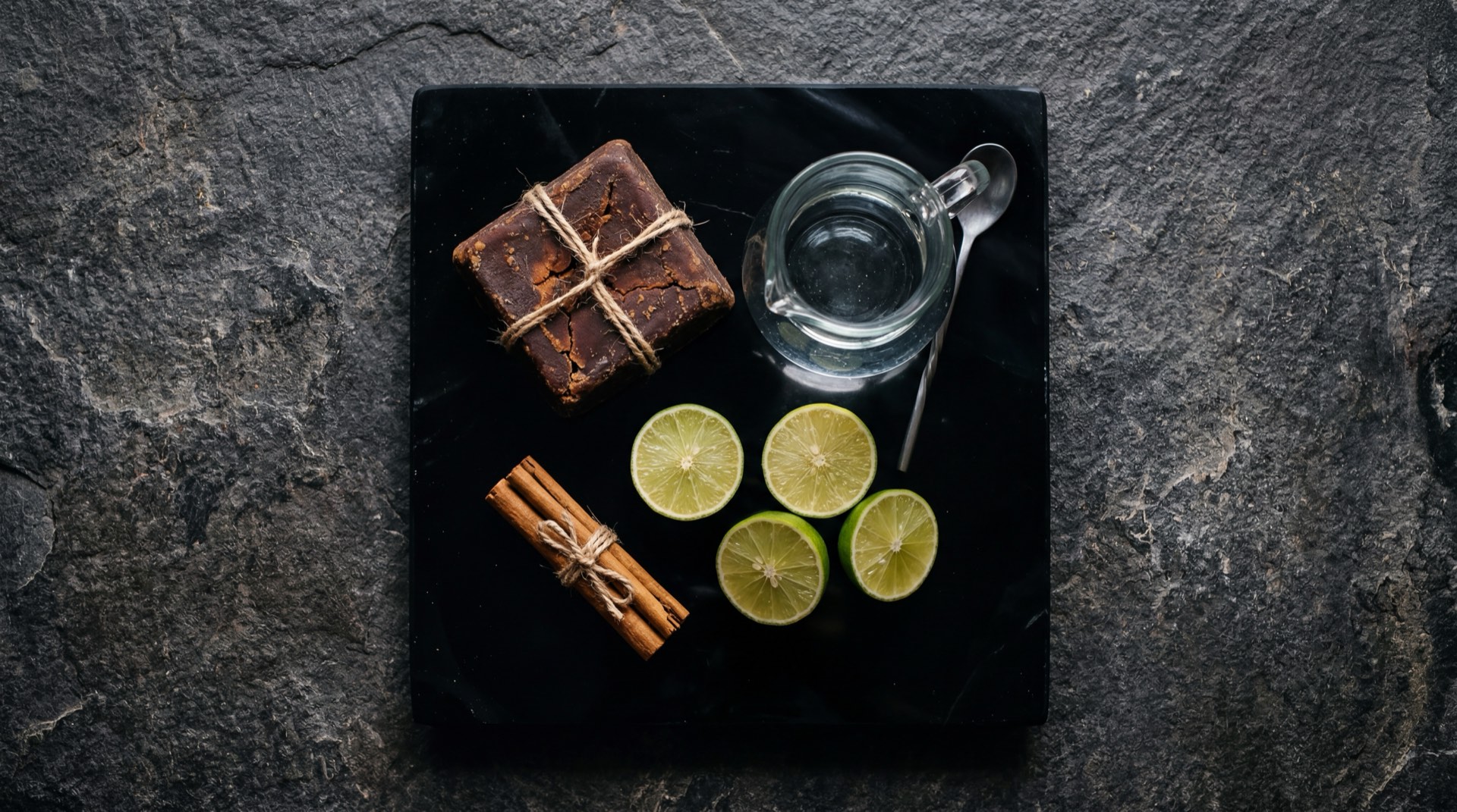 Ingredientes de la panela colombiana: cana de azucar fresca cortada en trozos, jugo de cana verde recien extraido y melaza de cana espesa sobre superficie oscura