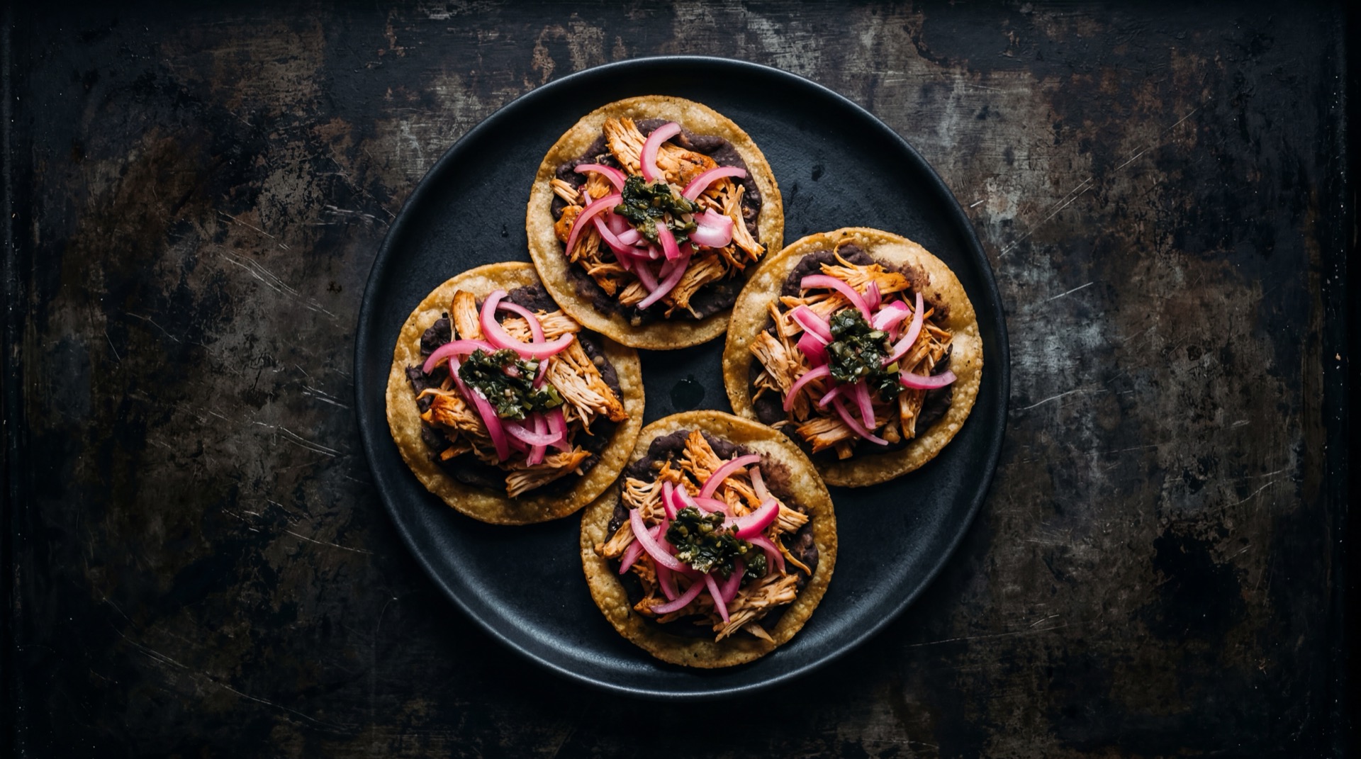 Panuchos mexicano tradicional servido en plato oscuro sobre mesa de marmol negro