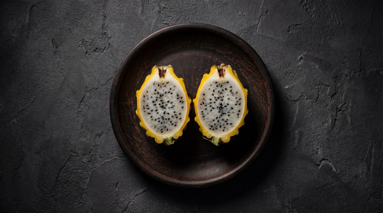 Pitahaya amarilla colombiana cortada mostrando pulpa blanca con semillas negras, fruta exotica rica en antioxidantes