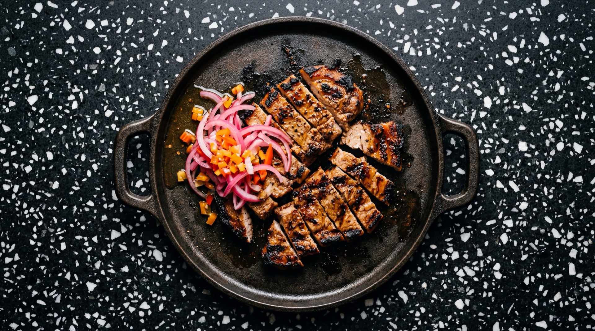 Poc Chuc mexicano tradicional servido en plato oscuro sobre mesa de marmol negro
