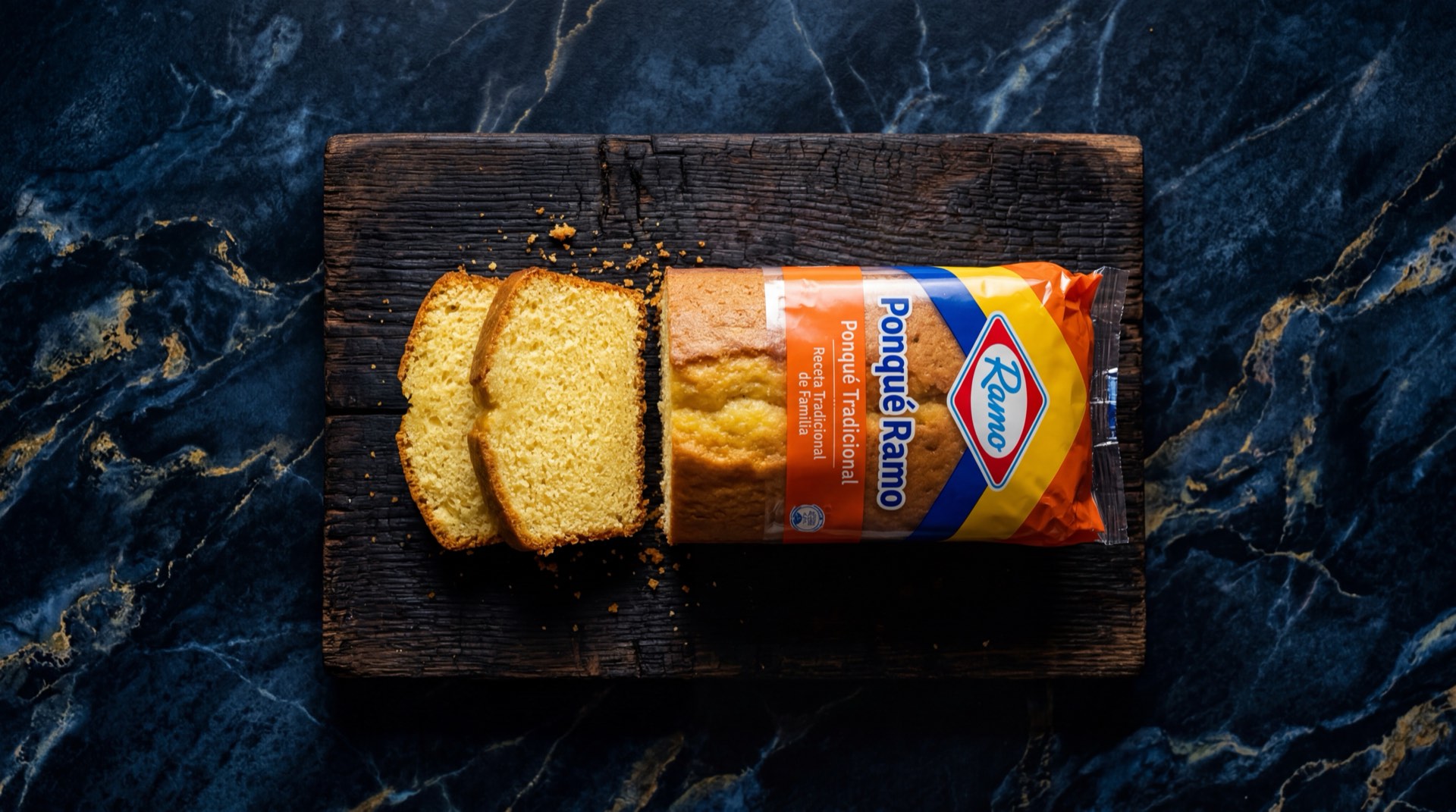 Ponque Ramo clasico de Productos Ramo S.A.S., tajada de ponque dorado sobre plato de ceramica oscura en mesa de marmol negro