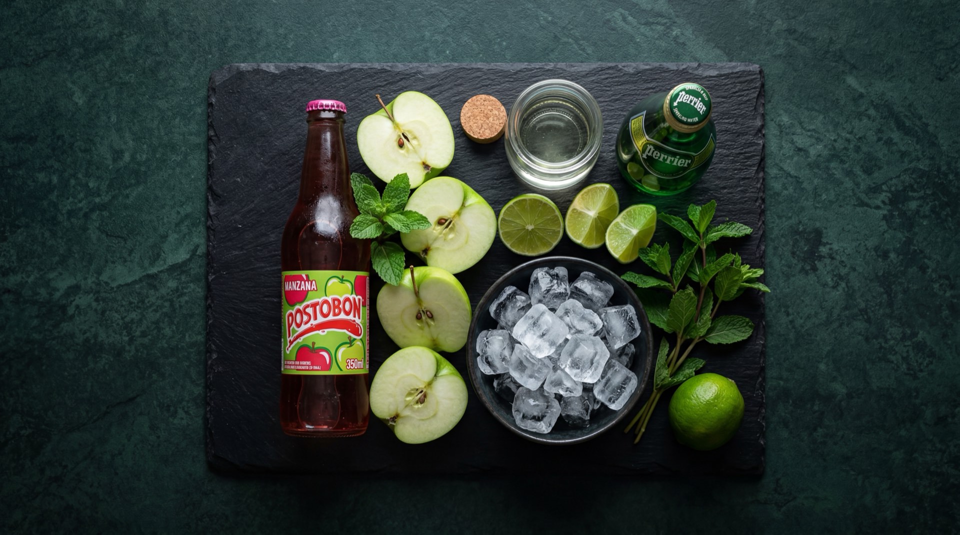Postobon Manzana servida en vaso de vidrio con hielo mostrando el liquido verde amarillento gasificado, con azucar refinada blanca y manzanas verdes frescas al lado