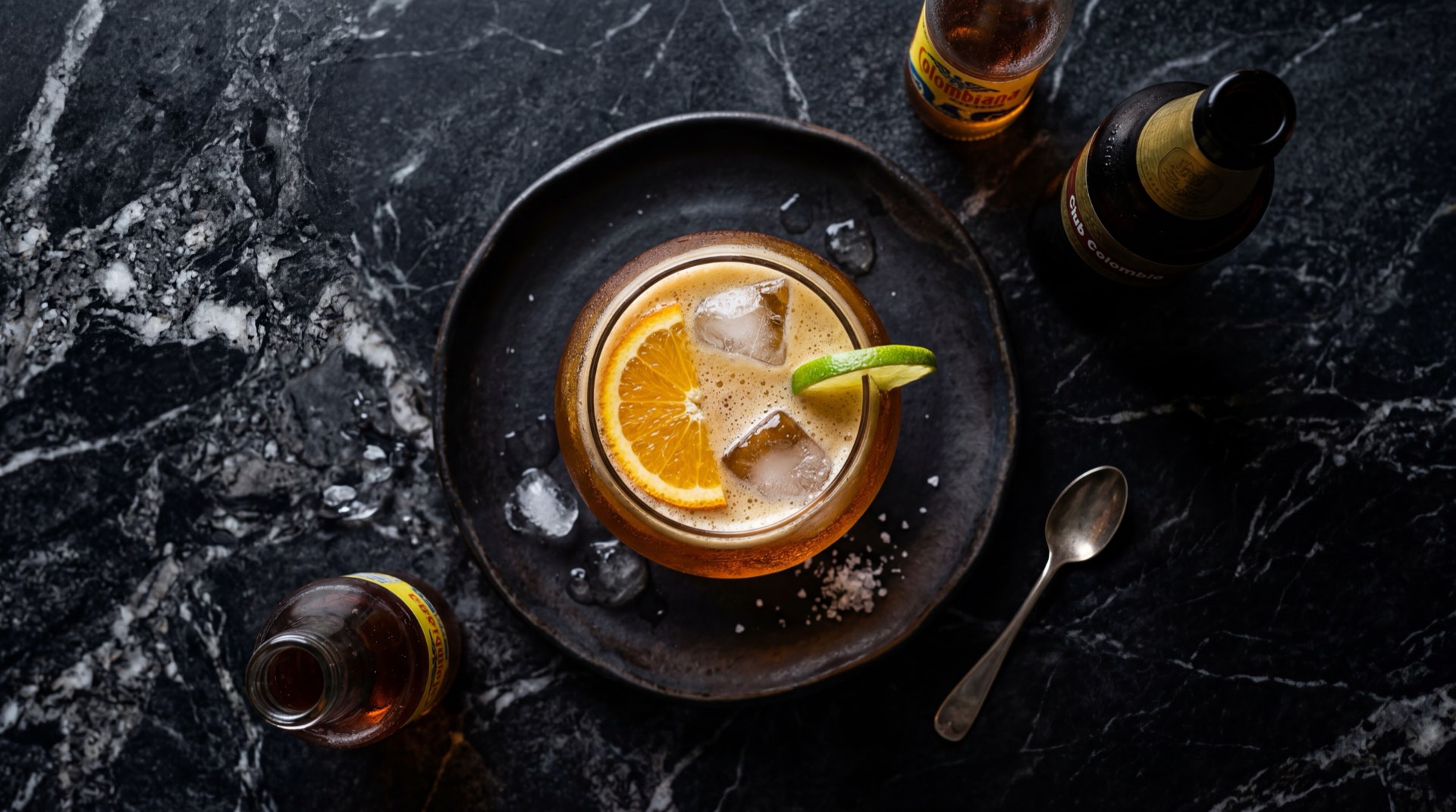 Vaso grande de refajo colombiano dorado espumoso con cerveza y gaseosa Colombiana sobre mesa de marmol nero marquina negro con vetas blancas