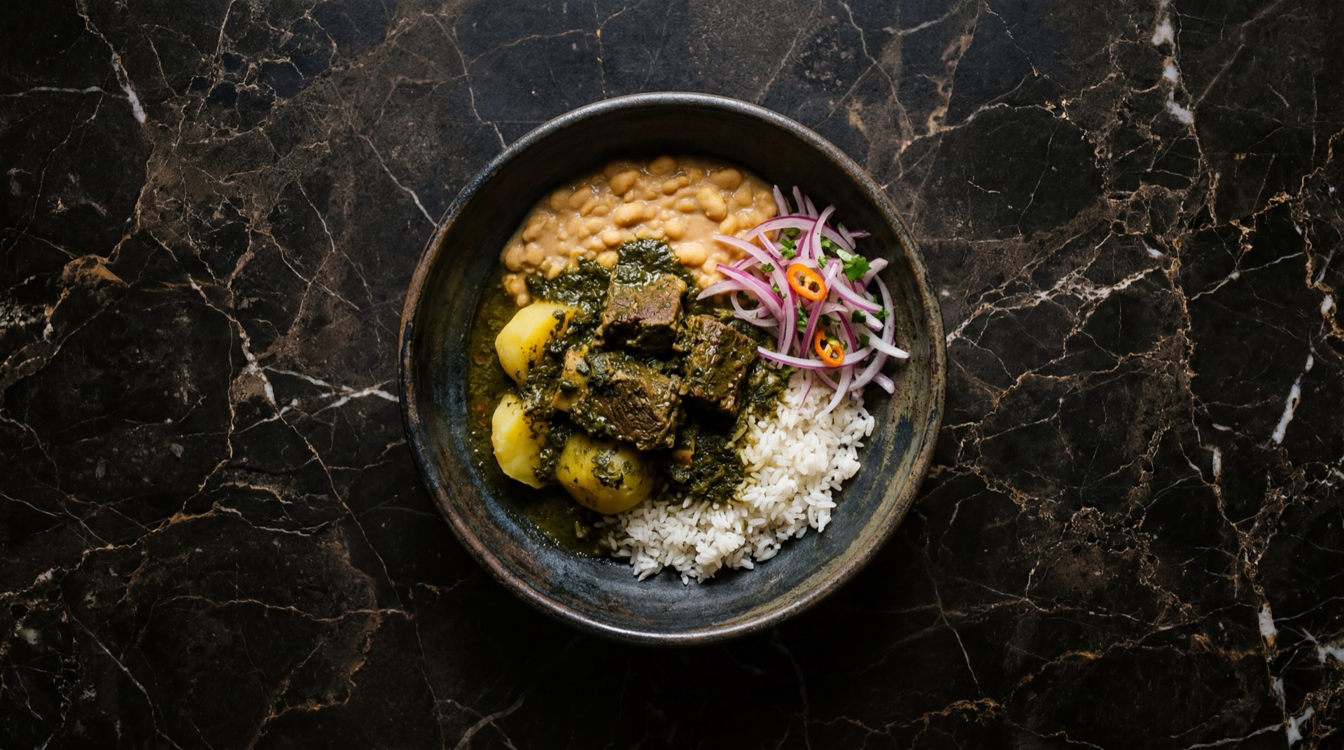 Seco de res peruano con salsa verde de cilantro fresco, frejoles canario guisados y arroz blanco cocido en cazuela de barro oscura sobre mesa de ebano