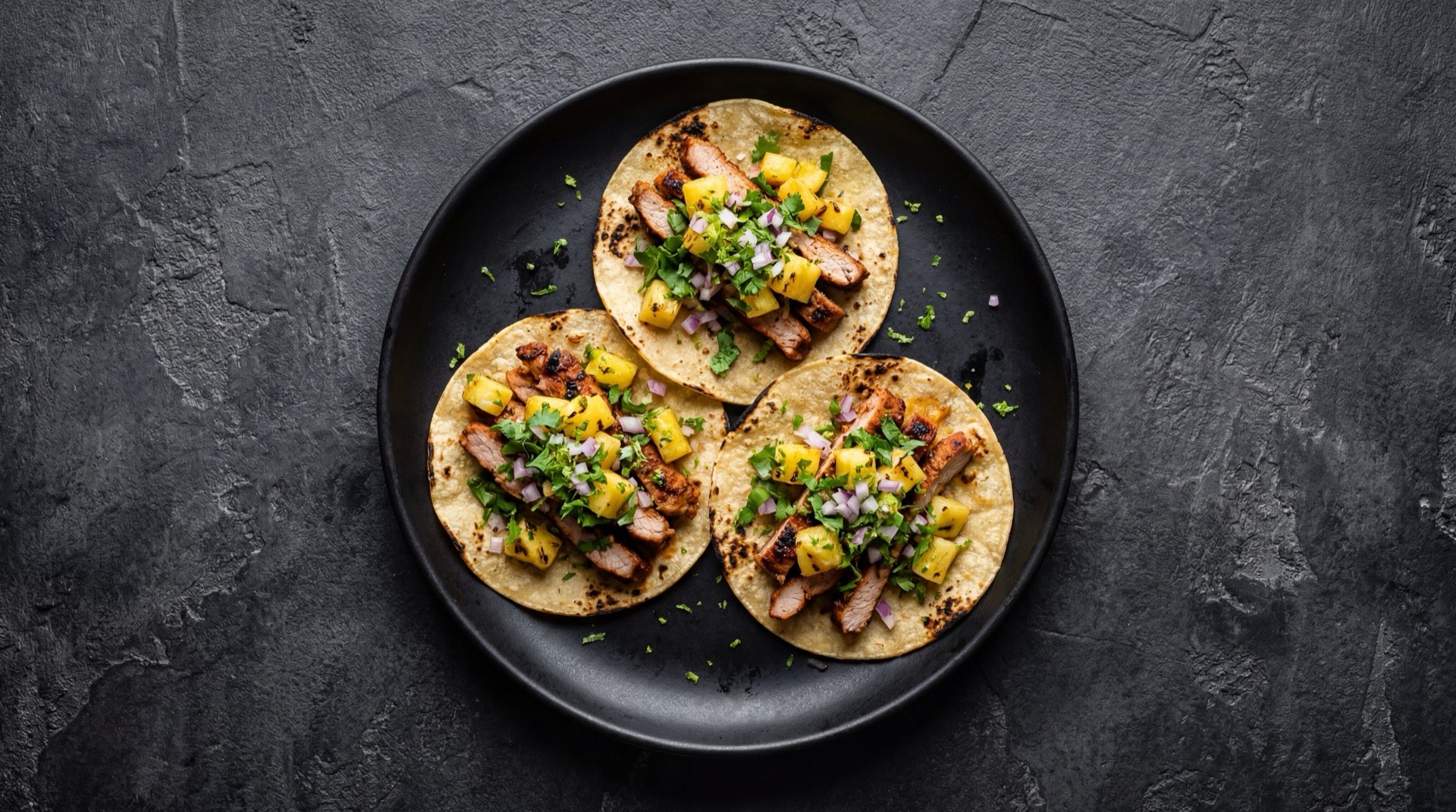 Tacos al pastor version saludable con carne de cerdo magra a la plancha, tortilla de maiz integral y abundante cilantro fresco con pina asada