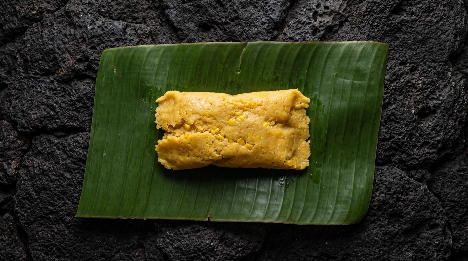 Tamales de Elote mexicano tradicional servido en plato oscuro sobre mesa de marmol negro