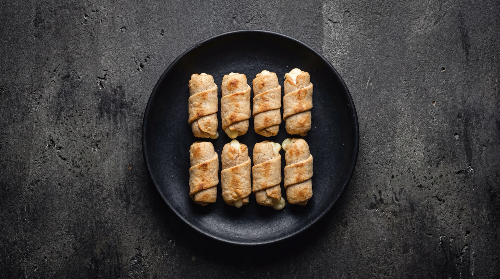 Tequenos venezolanos version saludable al horno dorados sobre rejilla metalica oscura sin exceso de aceite
