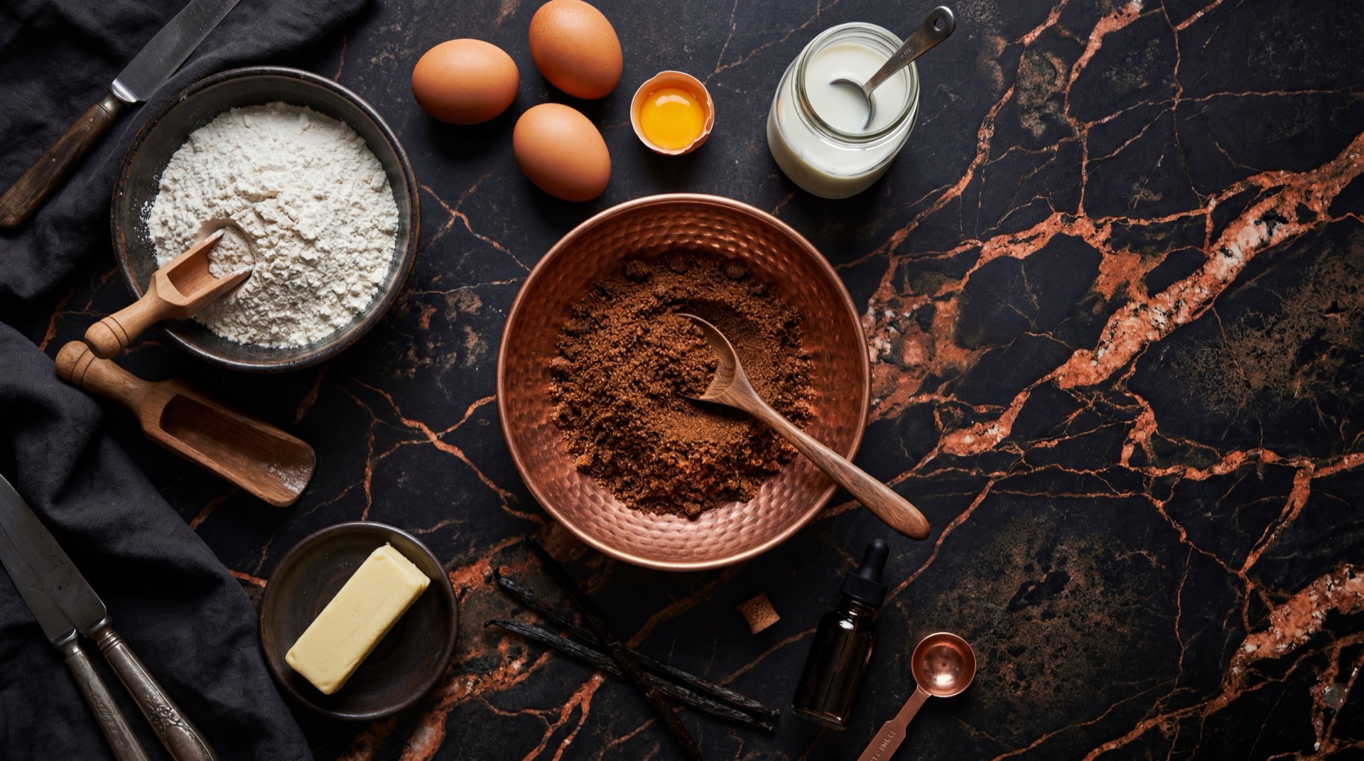 Ingredientes de la Tortiramo: harina de trigo fortificada, huevos frescos, azucar refinada, aceite vegetal, leche entera y esencia de vainilla sobre mesa oscura