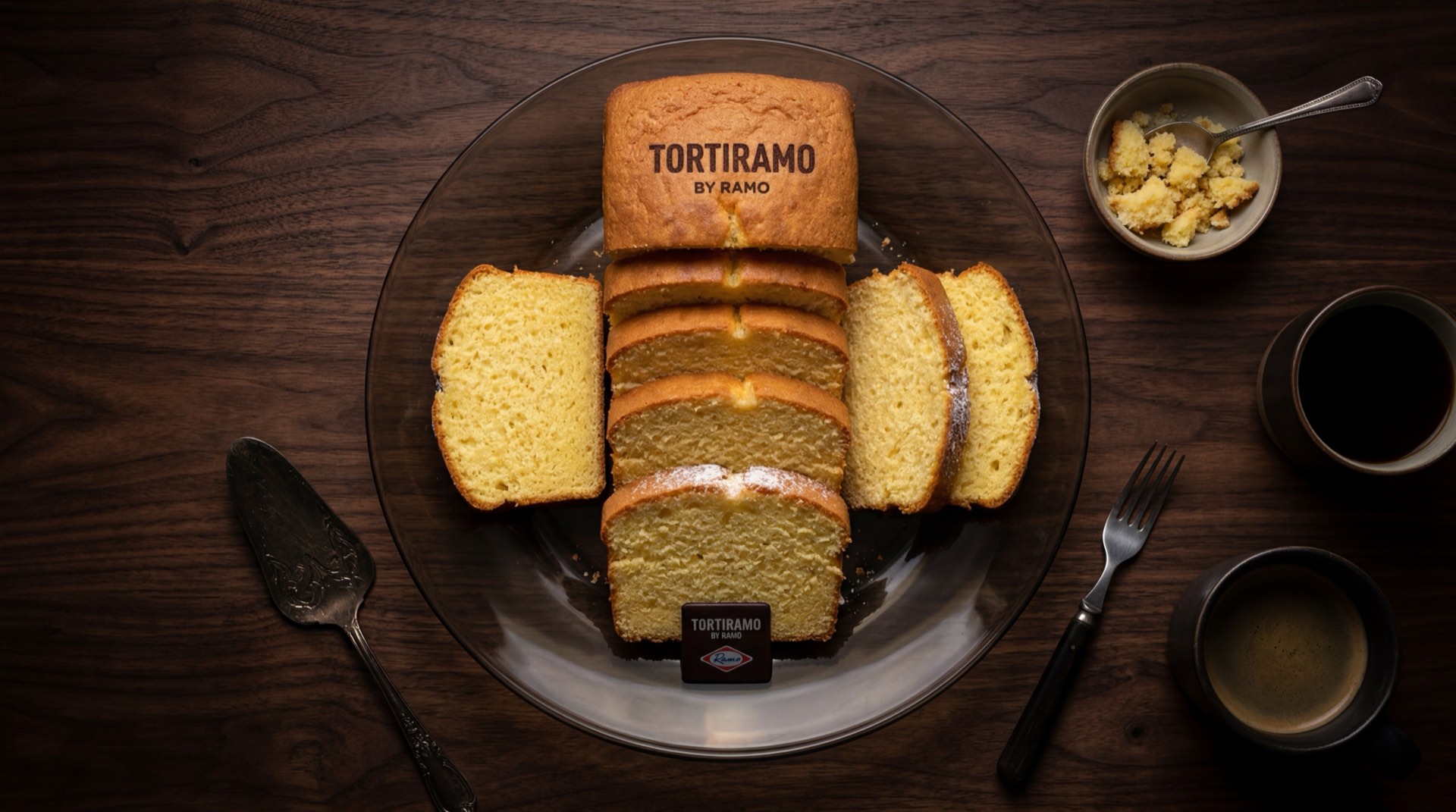Tortiramo de Ramo, torta de vainilla esponjosa amarilla sobre plato de ceramica negra en mesa de marmol oscuro
