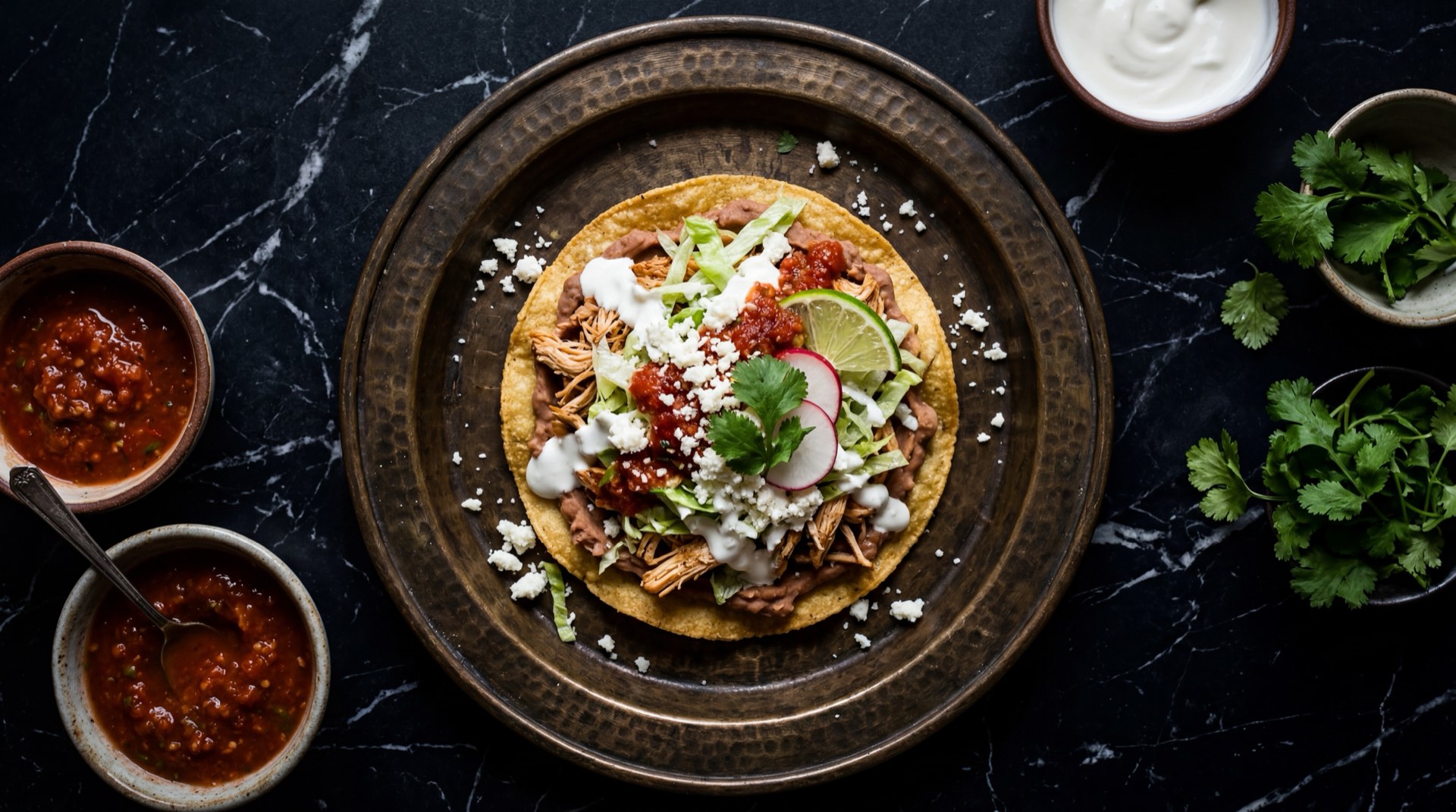 Ingredientes para tostadas mexicanas: tortillas de maiz frescas, pechuga de pollo desmenuzada, chiles chipotle adobados, tomates rojos maduros, frijoles negros refritos, lechuga iceberg, crema agria mexicana y queso fresco desmoronado